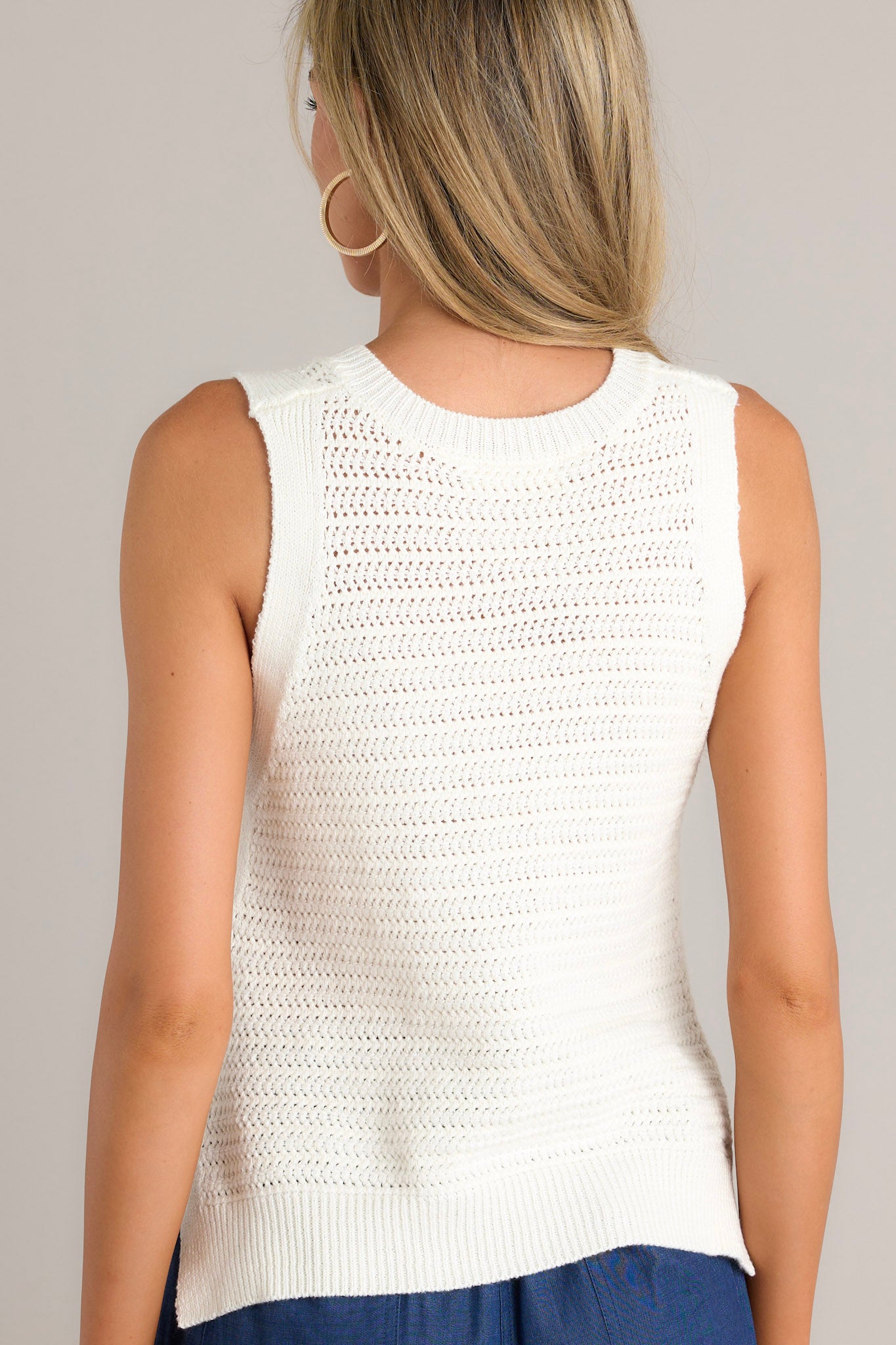 Back view of an ivory top highlighting the knit texture and the cropped length.