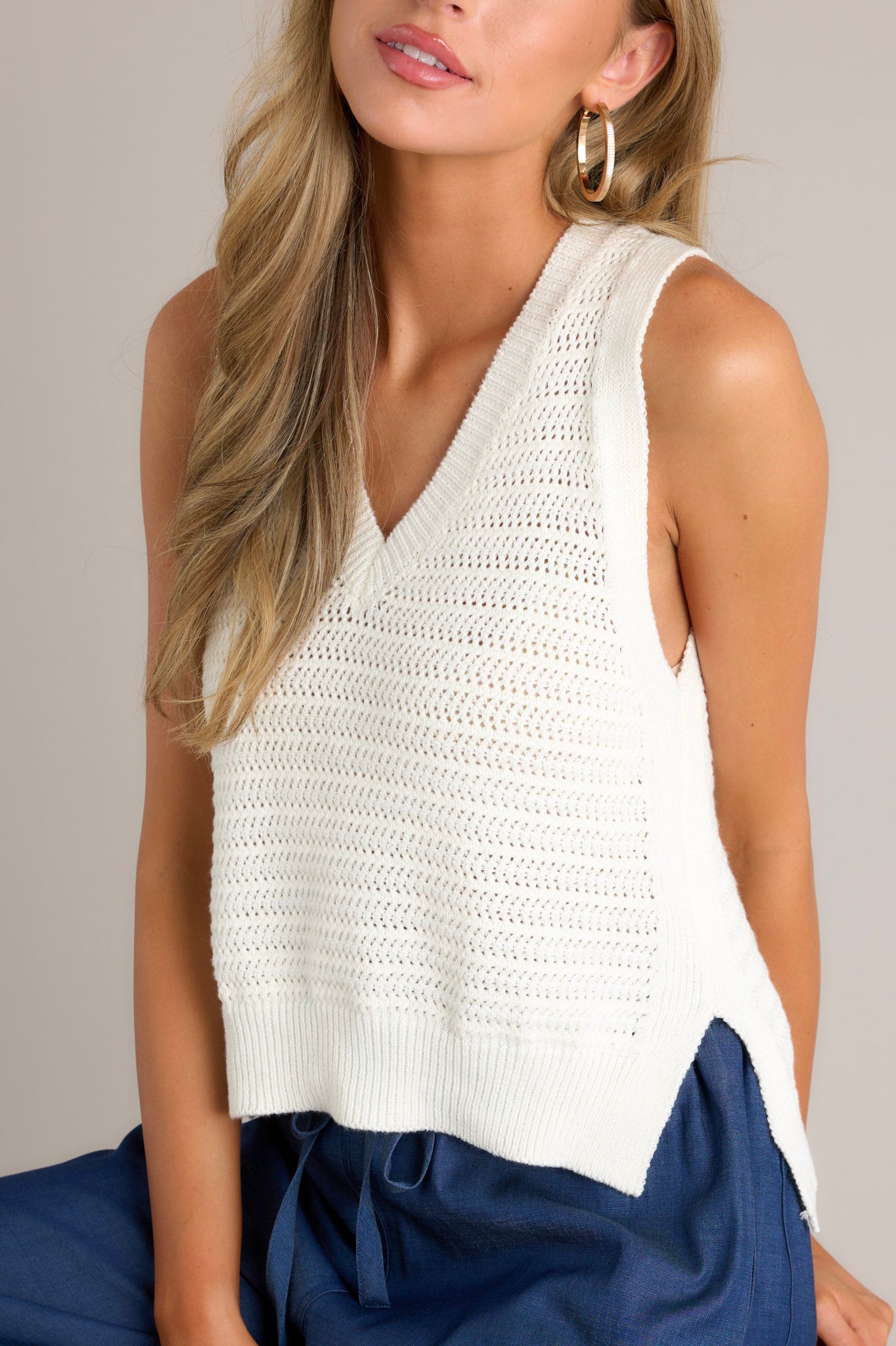 Close-up of the ivory top showing the v-neckline and the knit texture.