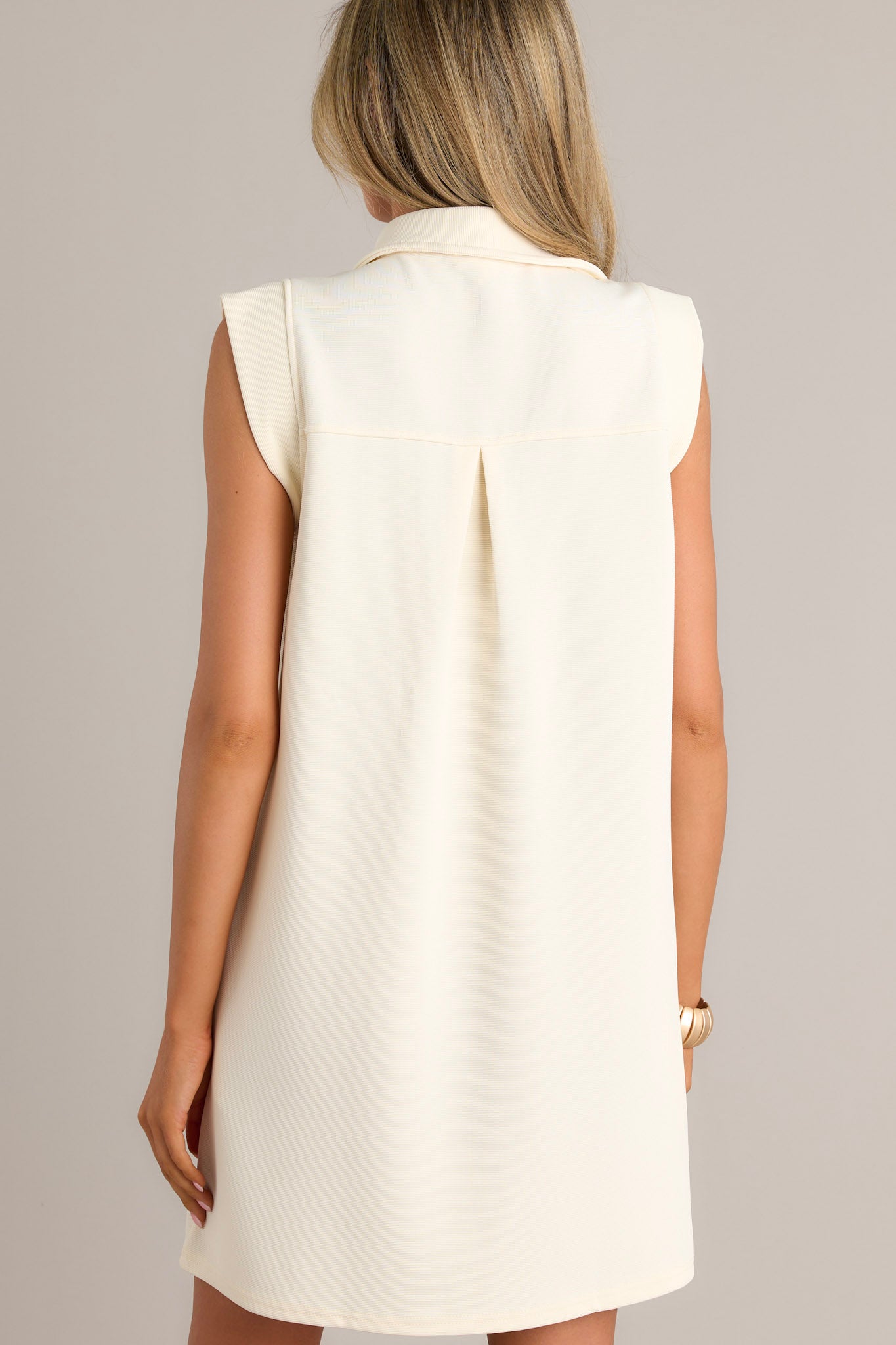 Back view of a beige mini dress highlighting the relaxed fit and sleeveless design.