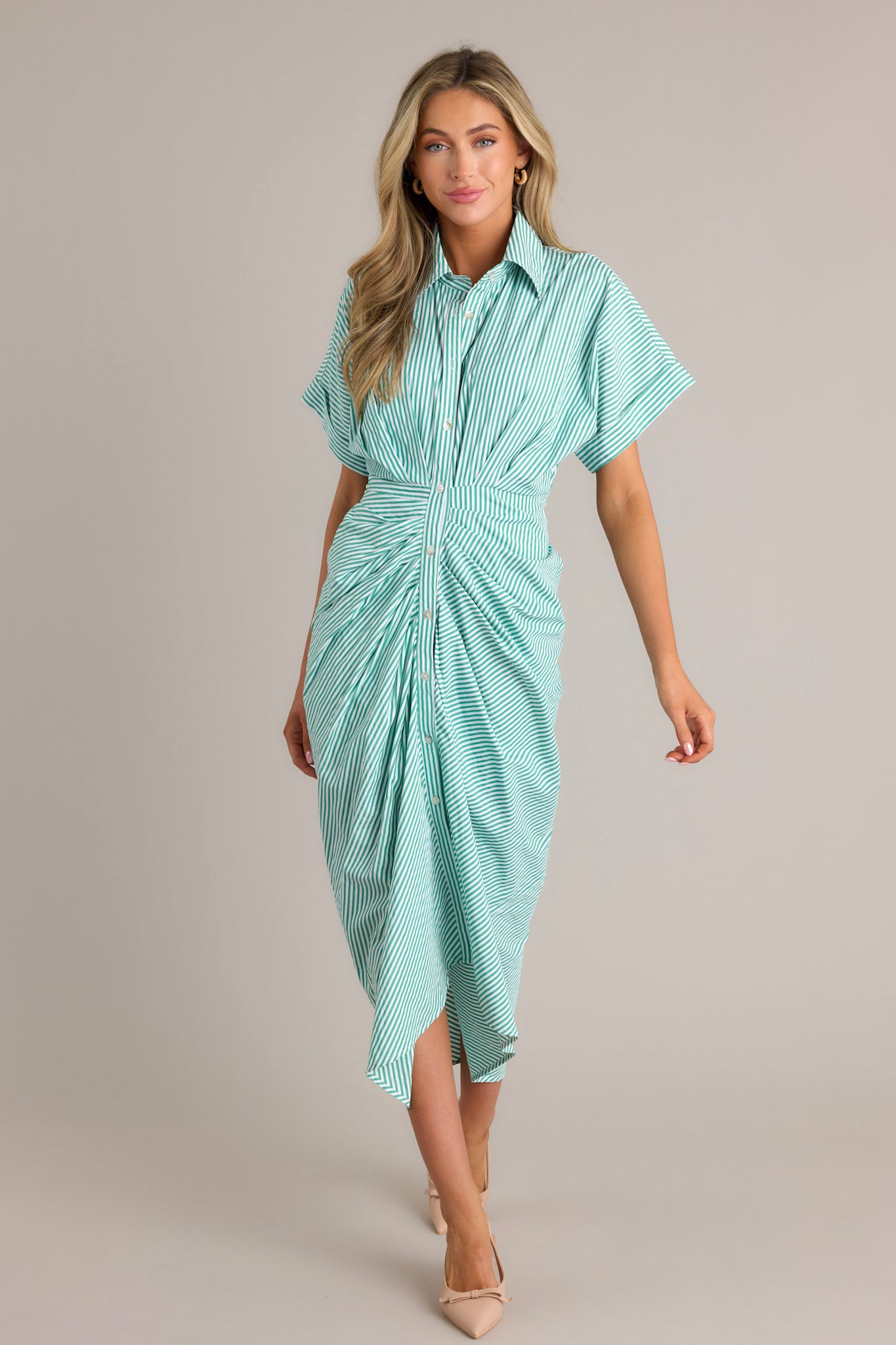 Action shot of a green stripe midi dress displaying the fit and movement, highlighting the collared neckline, full button front, self-tie waist feature, front slit, and short sleeves.