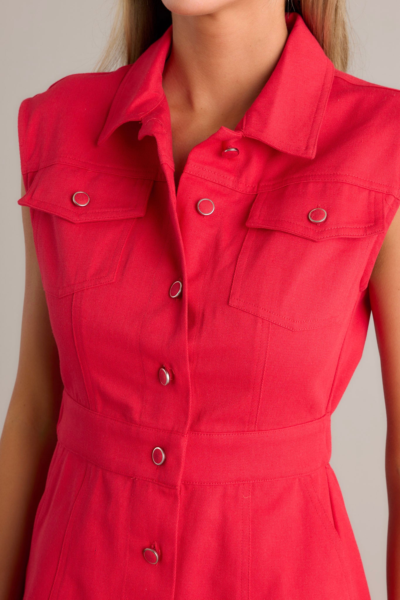 Close-up of the red mini dress showing the collared neckline, full button front, functional breast pockets, and the elastic insert in the back of the waist.