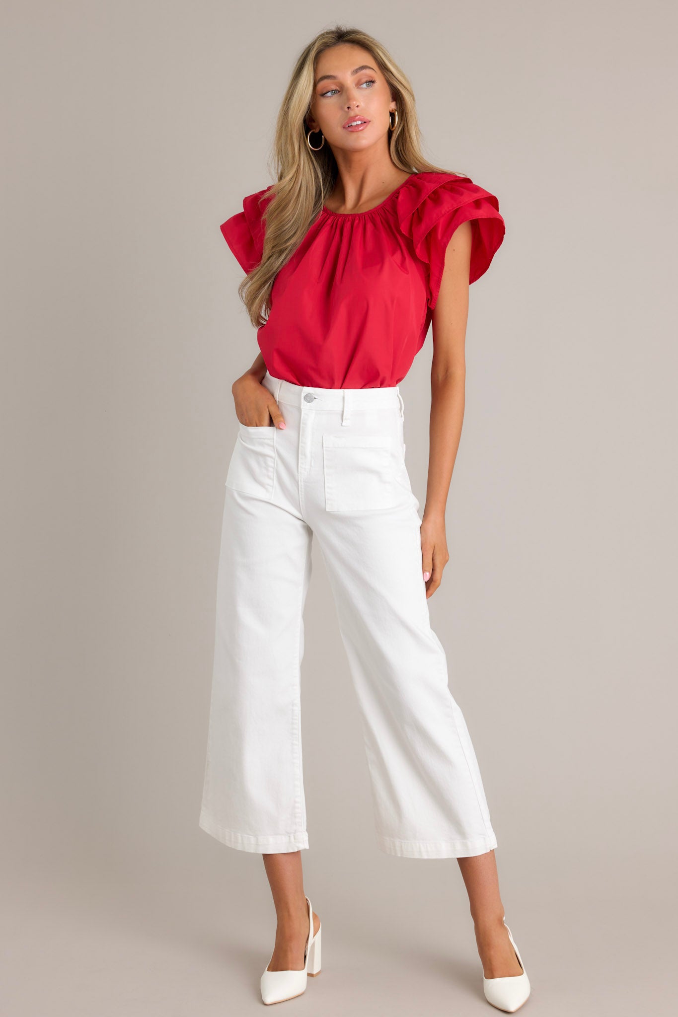 Front angled view of a red top featuring a rounded neckline, gathering at the neckline, a keyhole with a button closure, and ruffled short sleeves