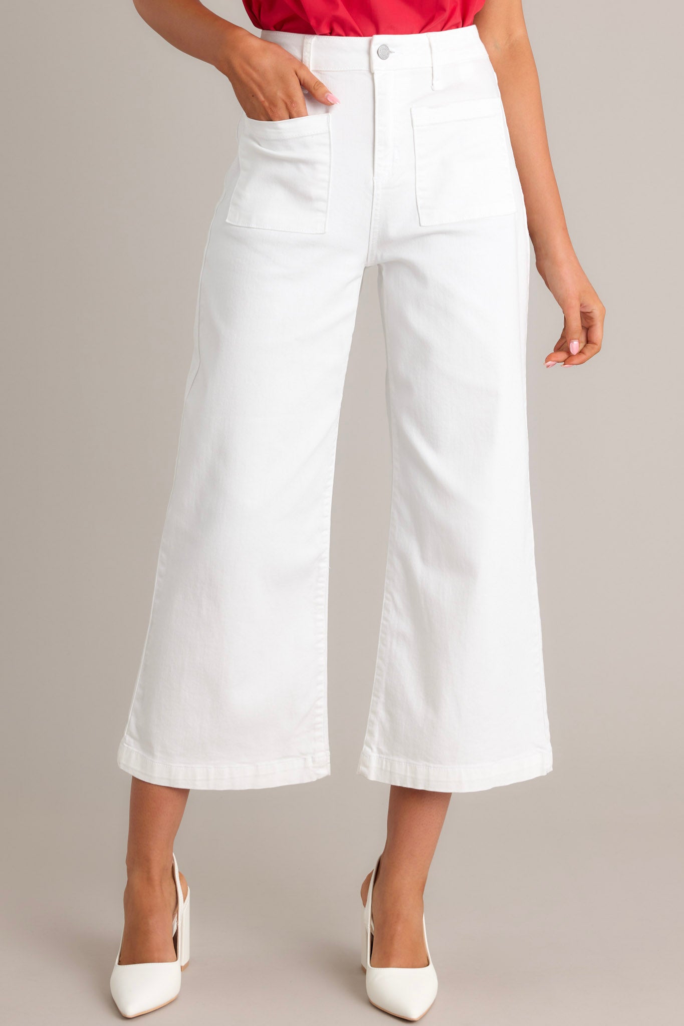 Front view of white jeans featuring a high waisted design, a button & zipper closure, belt loops, functional front & back pockets, a cropped hemline, and a flared leg.
