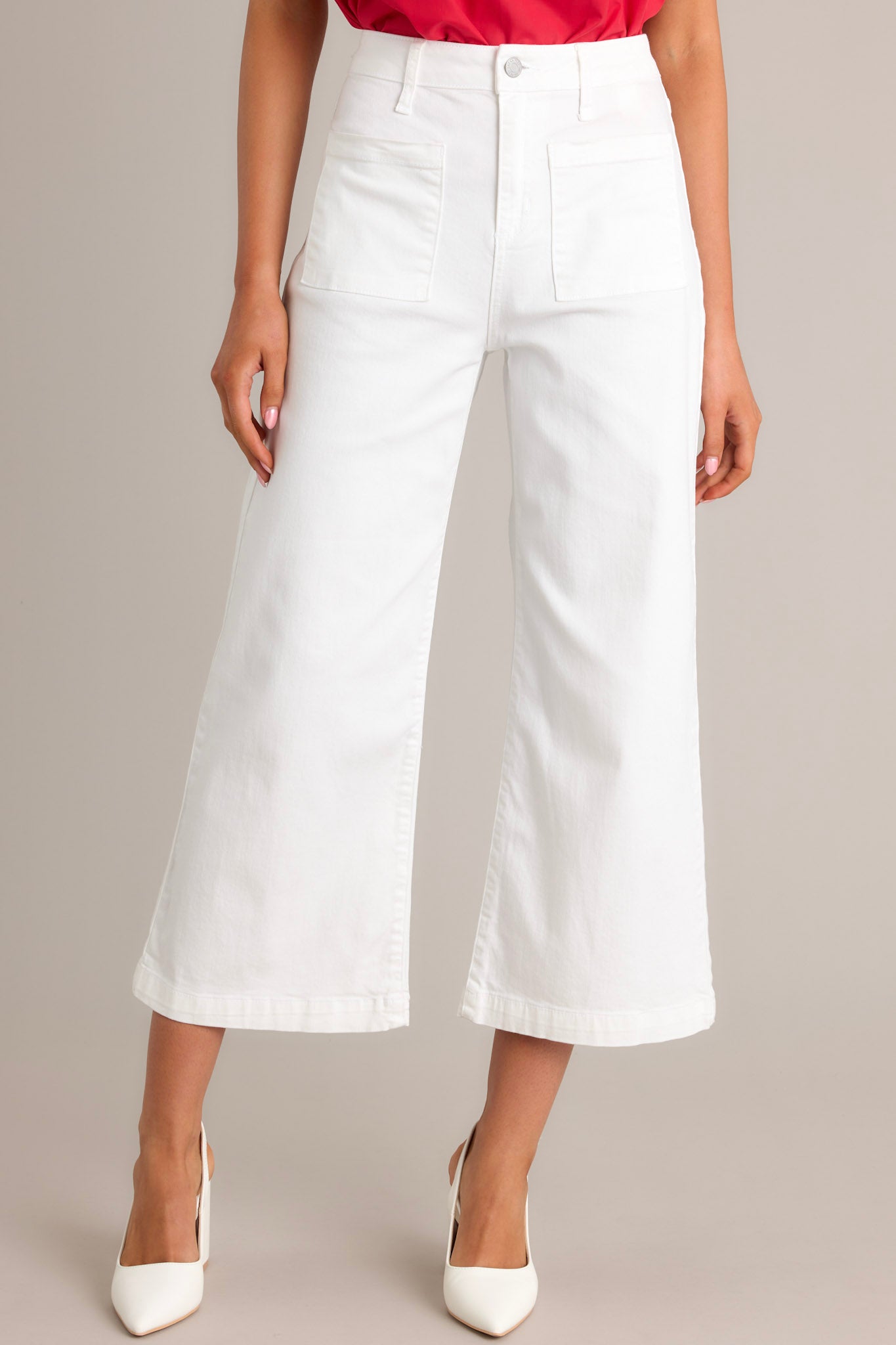 Front angled view of white jeans featuring a high waisted design, a button & zipper closure, belt loops, functional front & back pockets, a cropped hemline, and a flared leg