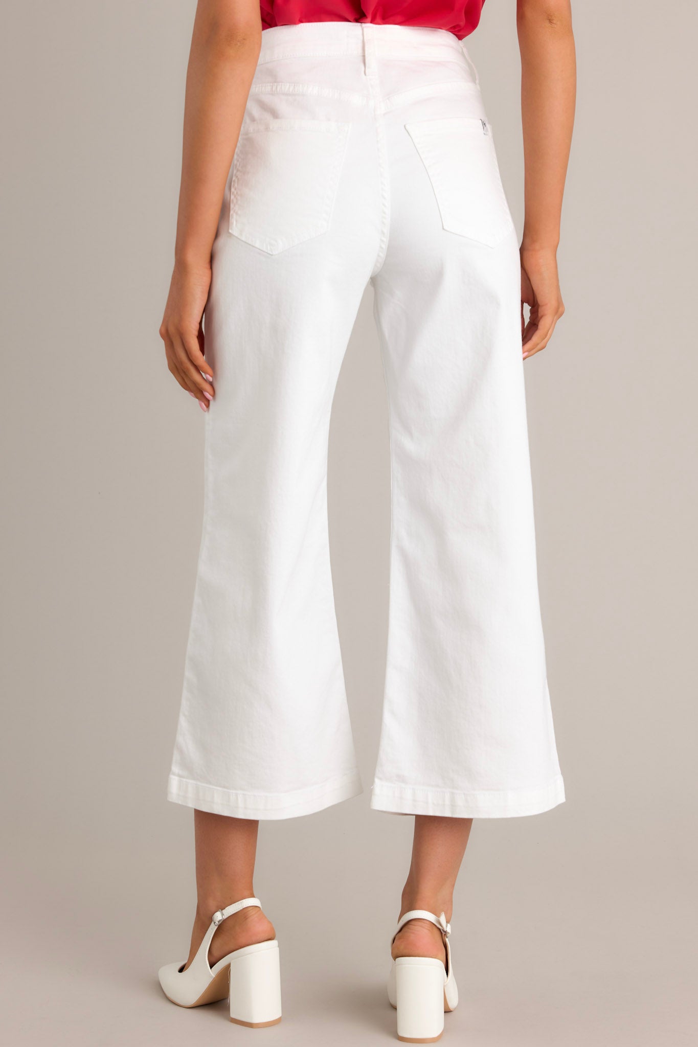 Close-up of the white jeans showing the button & zipper closure, belt loops, and functional front pockets.