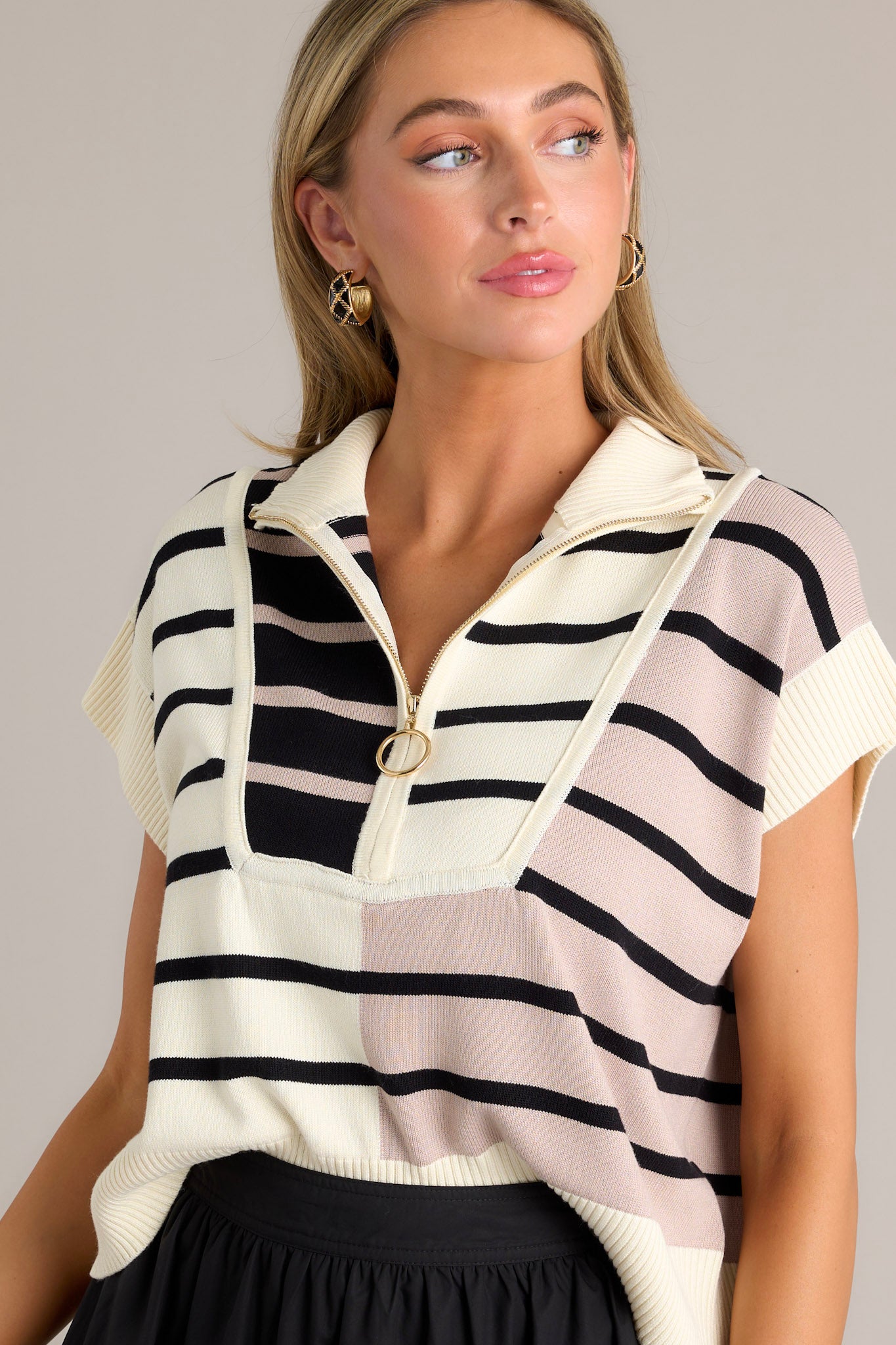 This beige sweater features a ribbed collared neckline, gold hardware, a functional half zip design, a bold striped design, ribbed cap sleeves, and and a ribbed hemline.