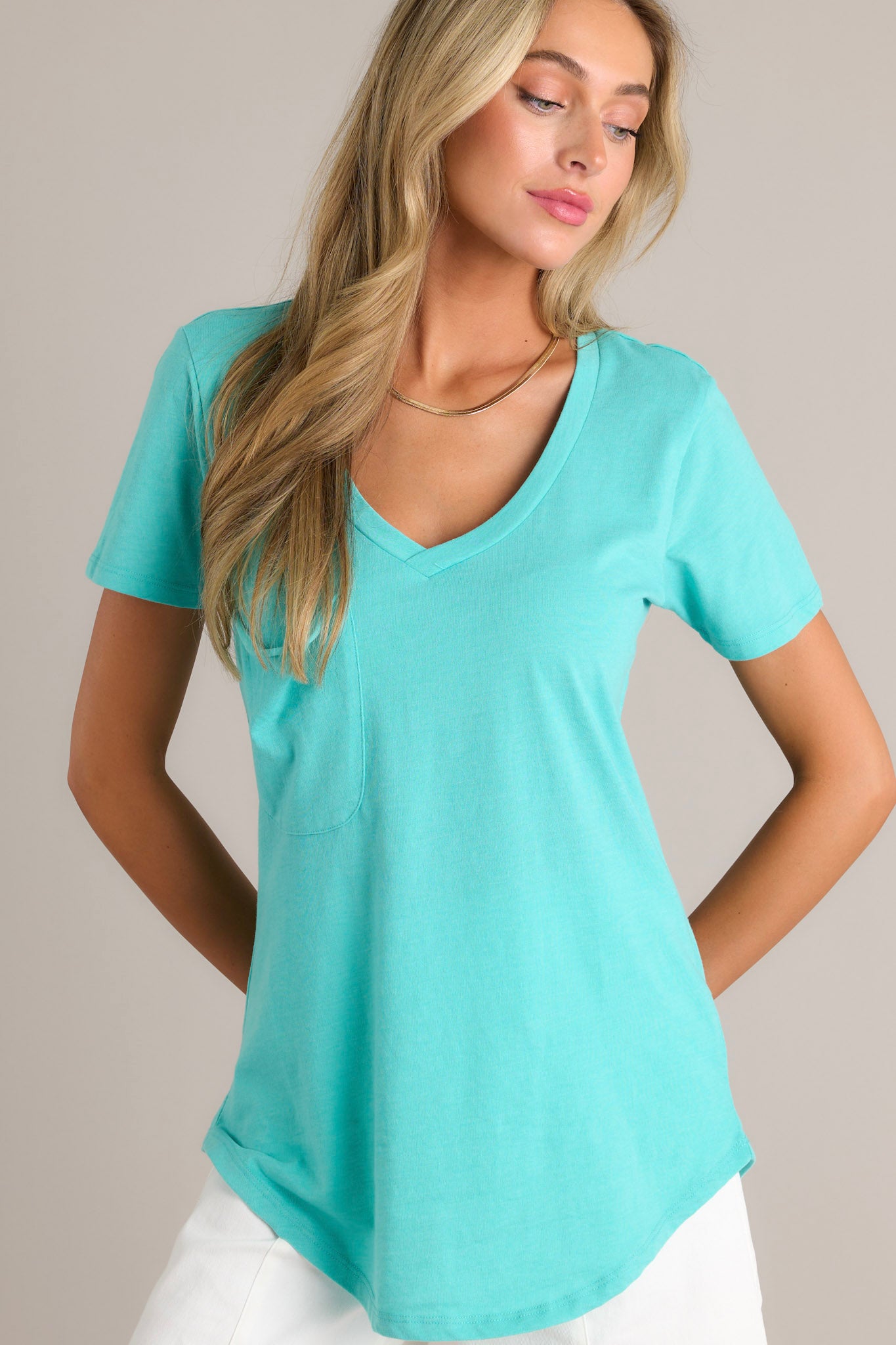 Front angled view of a cabana green tee featuring a v-neckline, a functional chest pocket, super soft fabric, and a scooped hemline