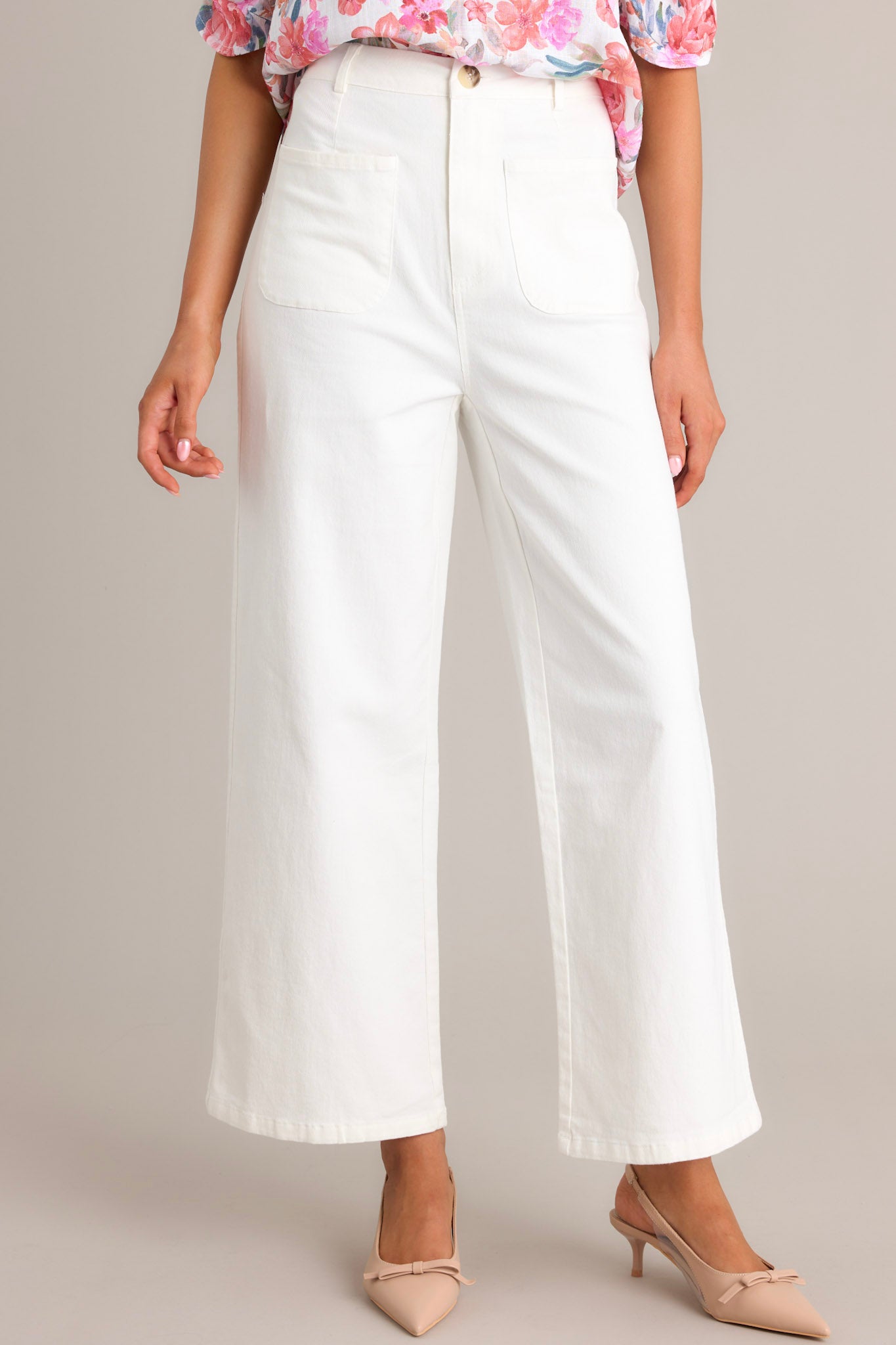 Front angled view of ivory jeans featuring a high waisted design, classic button & zipper closure, belt loops, functional front pockets, faux back pockets, and a wide leg design