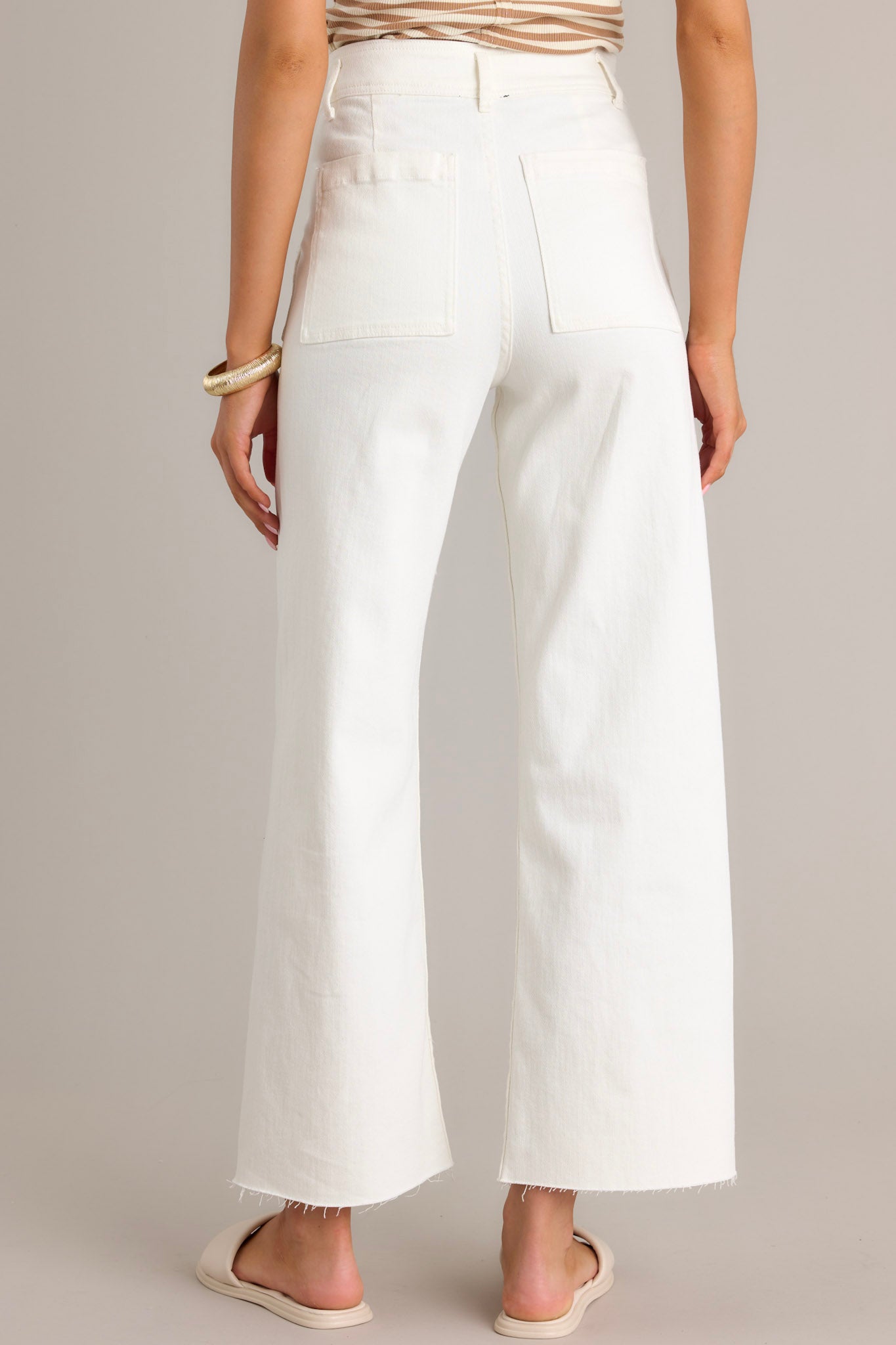 Back view of white jeans featuring functional back pockets, belt loops, and a wide leg design.