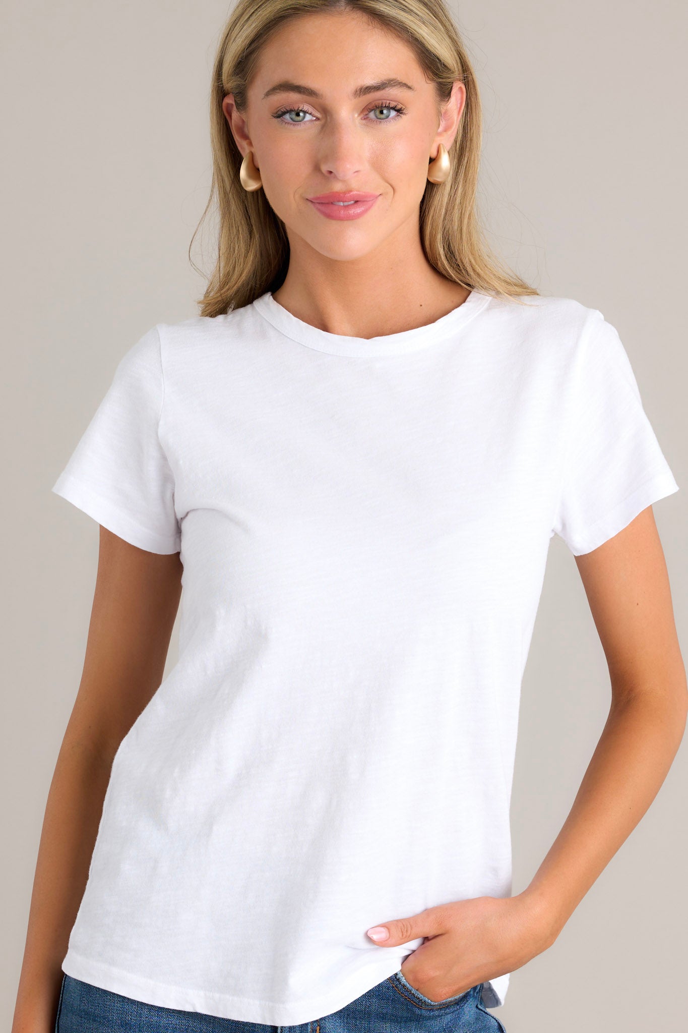 Front view of  this top that features a high crew neckline, lightweight material, an intentional exposed seam in the back, and short sleeves.