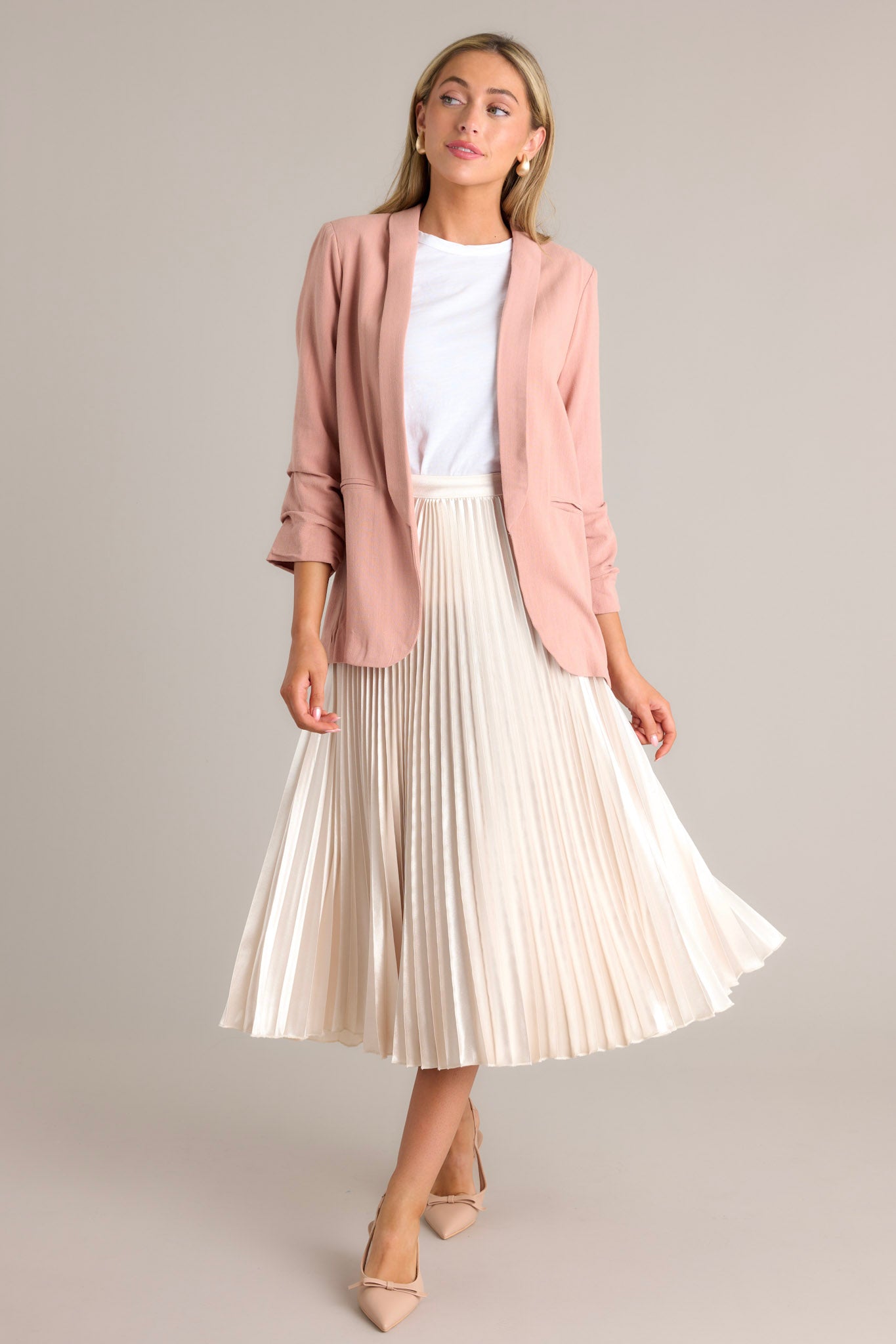 Front view of this dusty rose blazer featuring a folded neckline, shoulder padding, faux pockets, and gathering in the quarter-length sleeves.