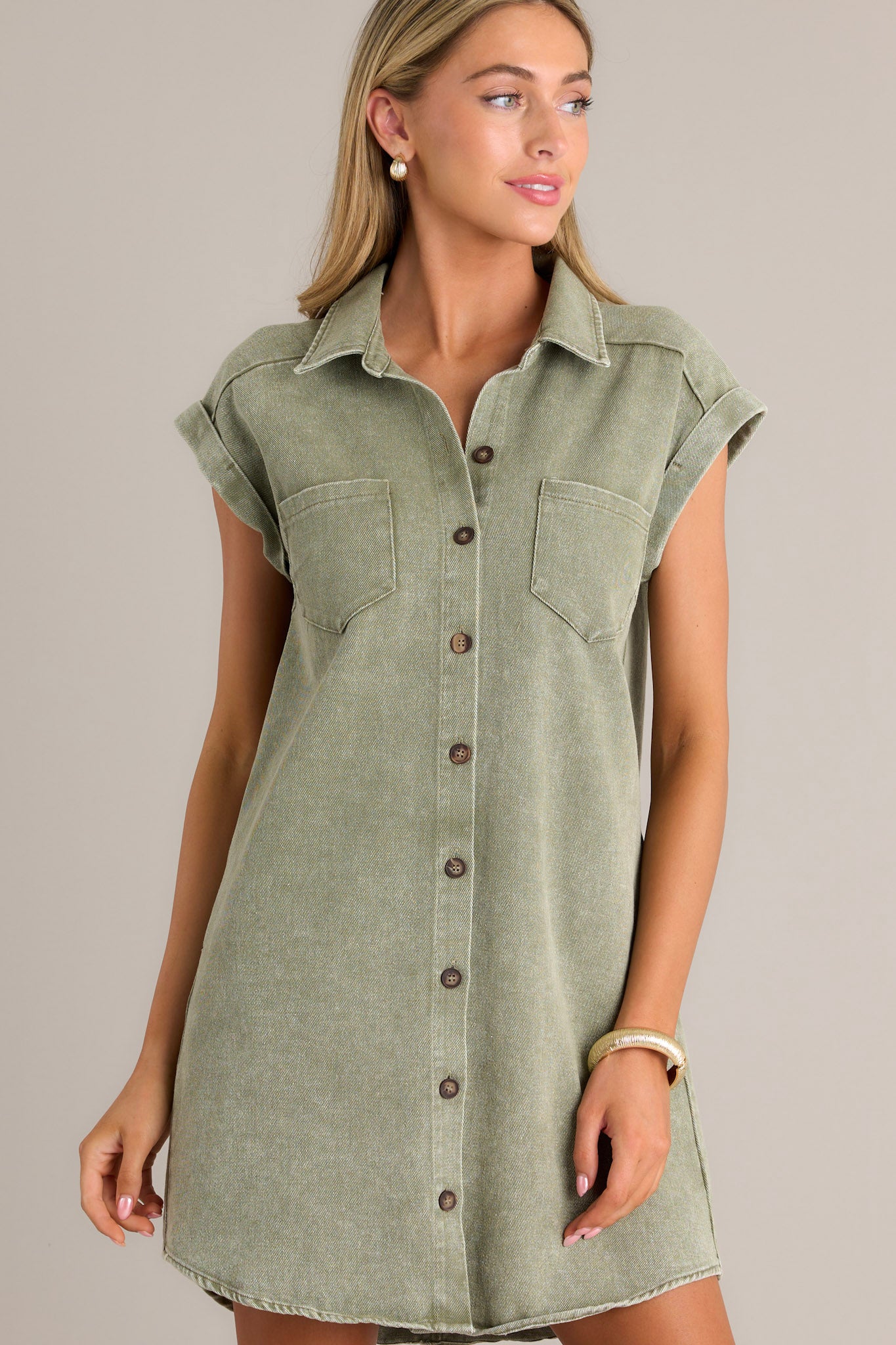 Side view of a green mini dress showcasing the collared neckline, full button front, functional breast & hip pockets, and folded short sleeves.