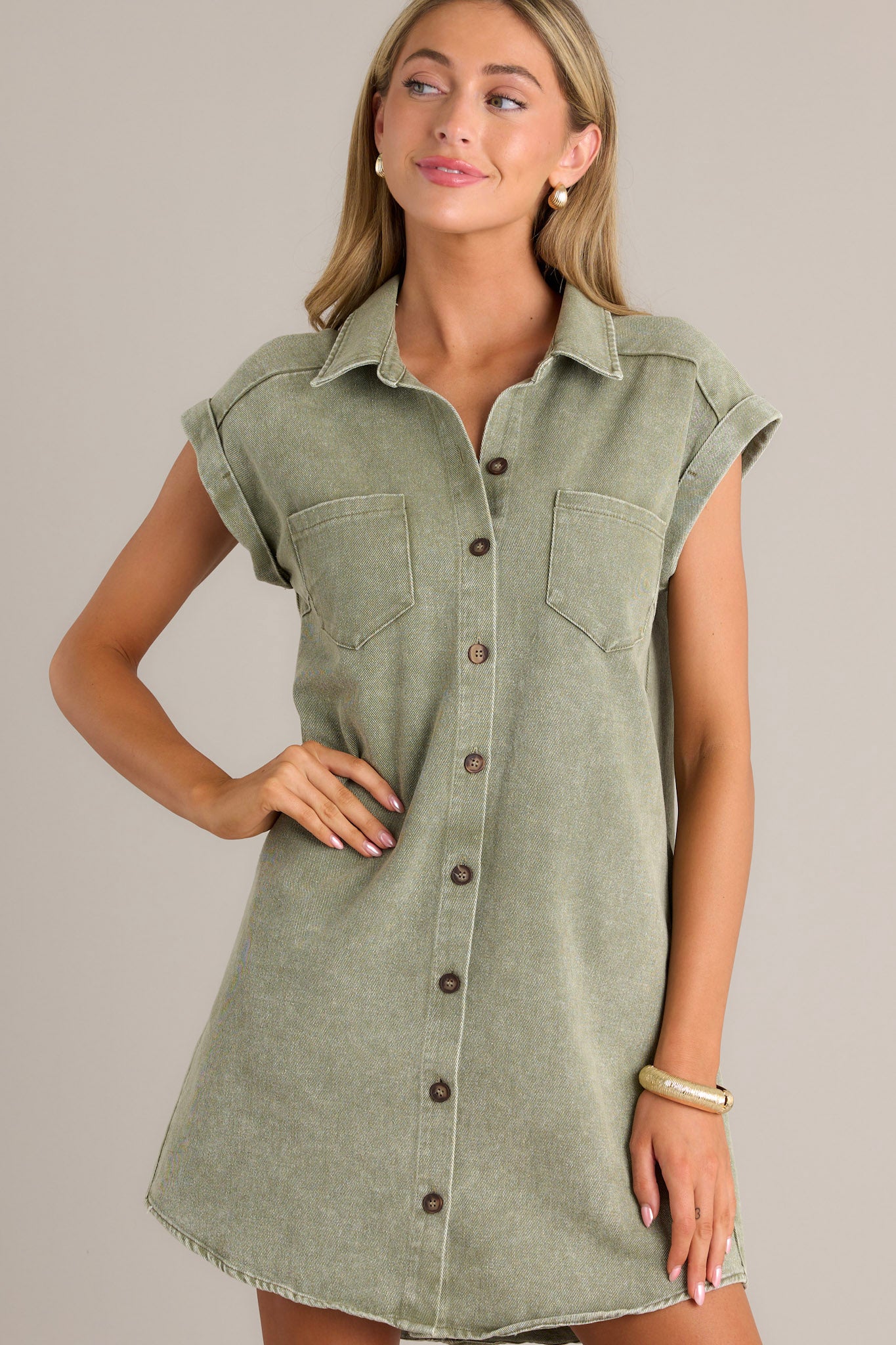 Front view of a green mini dress featuring a collared neckline, a full button front, functional breast & hip pockets, and folded short sleeves.