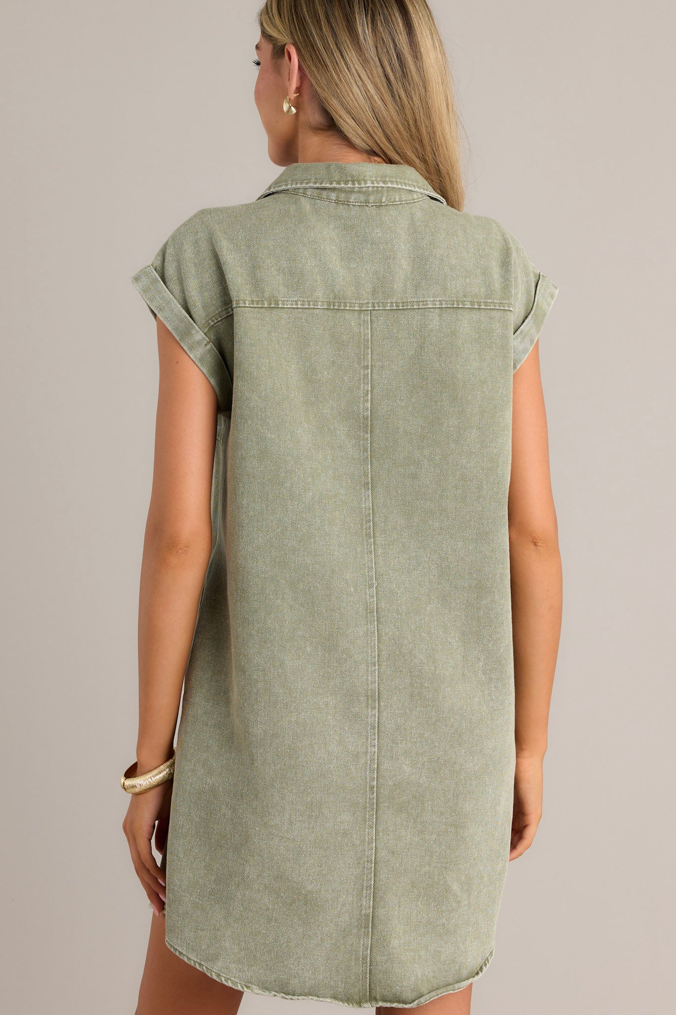 Back view of a green mini dress highlighting the collared neckline, folded short sleeves, and overall fit.