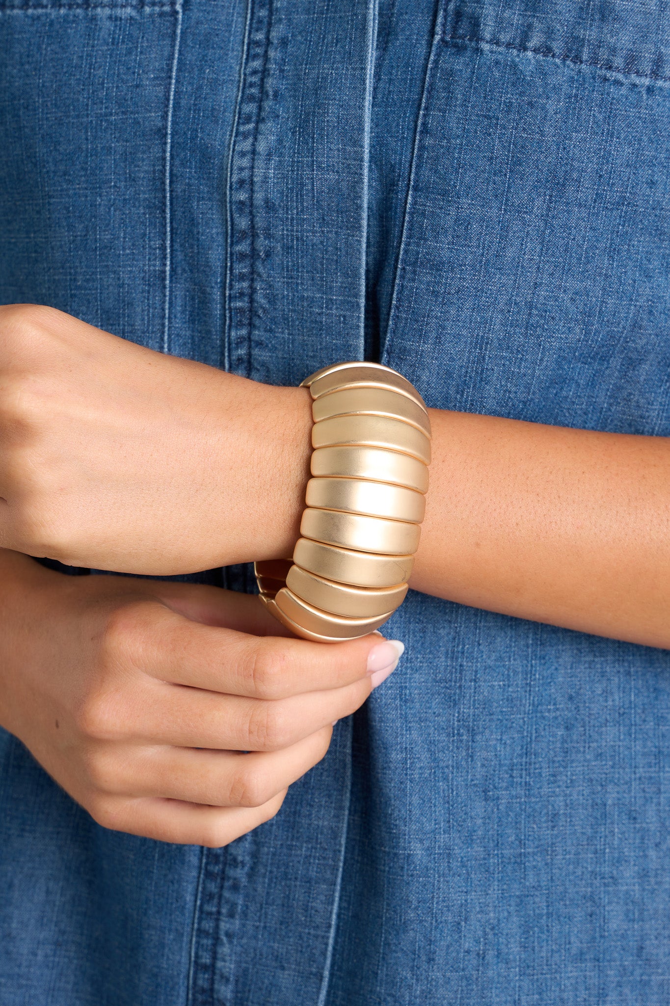 Close up view of this bracelet featuring gold hardware, curved horizontal beading, and an elastic band underneath.