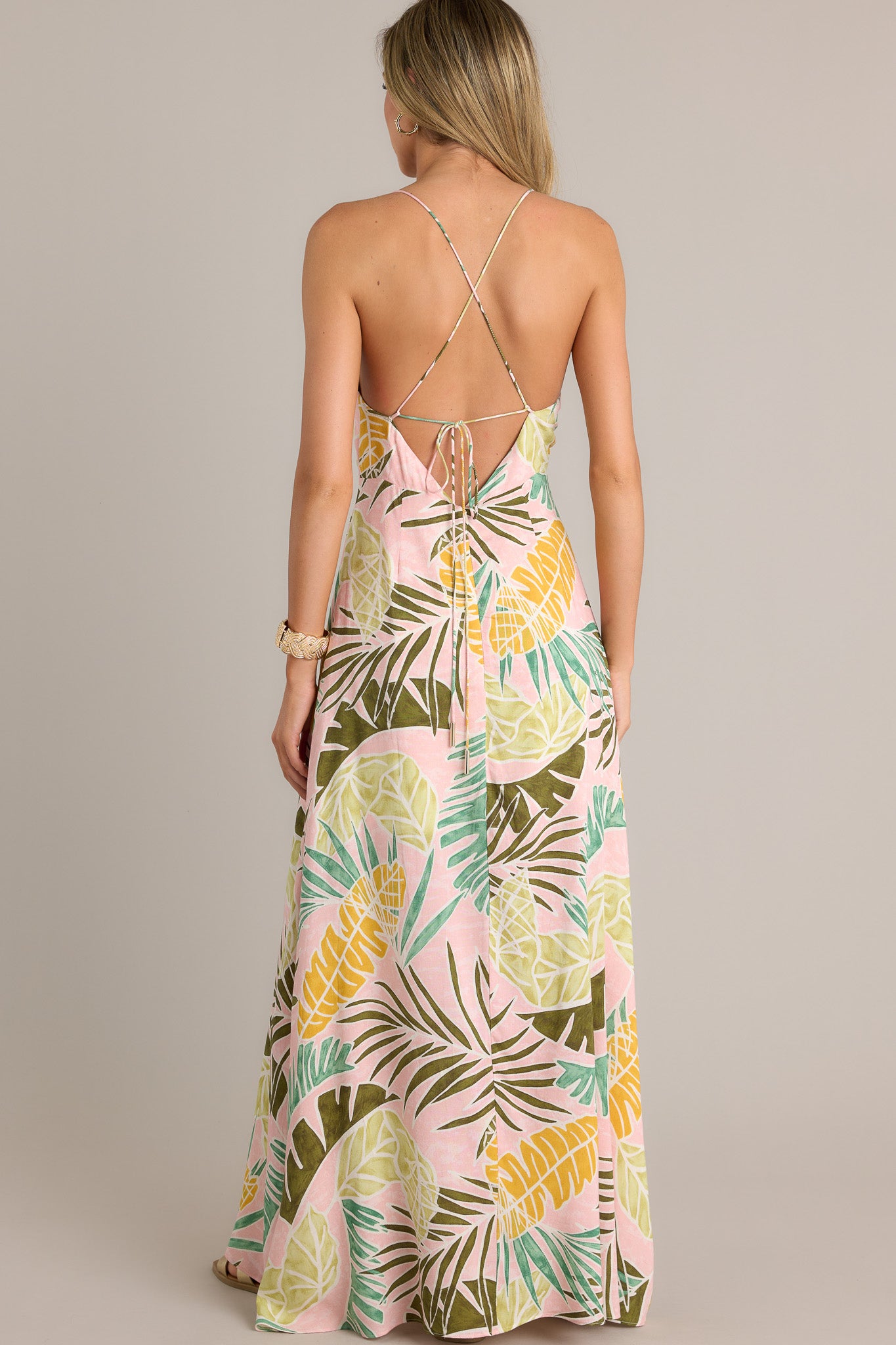 Back view of a light pink maxi dress highlighting the low back, thin adjustable self-tie straps, and overall fit.