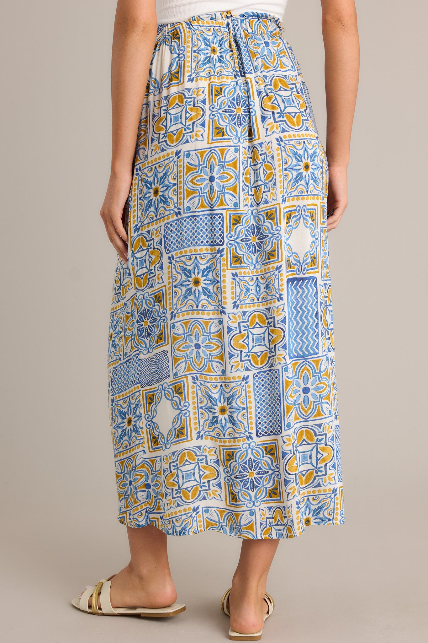 Back view of a blue maxi skirt highlighting the overall fit, open front, and unique print.