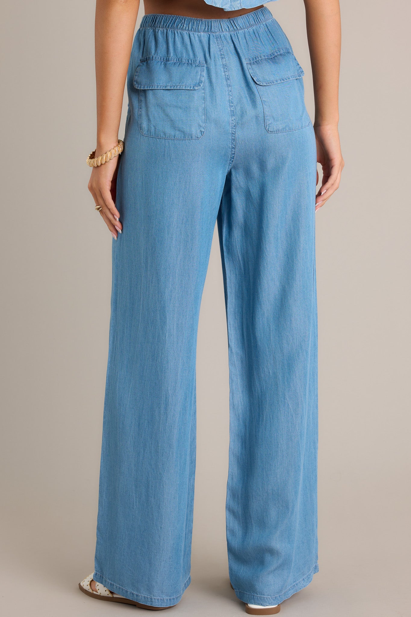 Back view of chambray pants highlighting the elastic waistband, self-tied drawstring, functional back pockets, and overall fit.