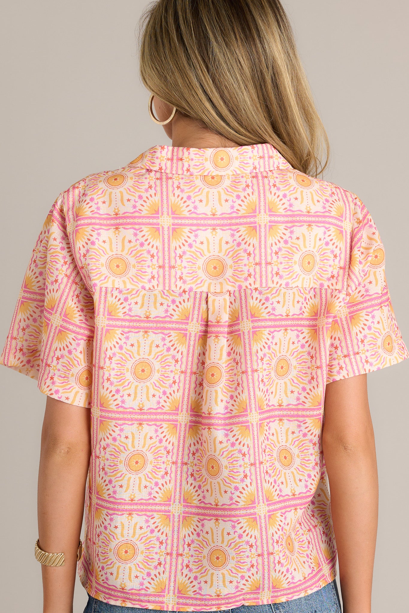 Back view of a pink top highlighting the overall fit, short sleeves, and unique print.