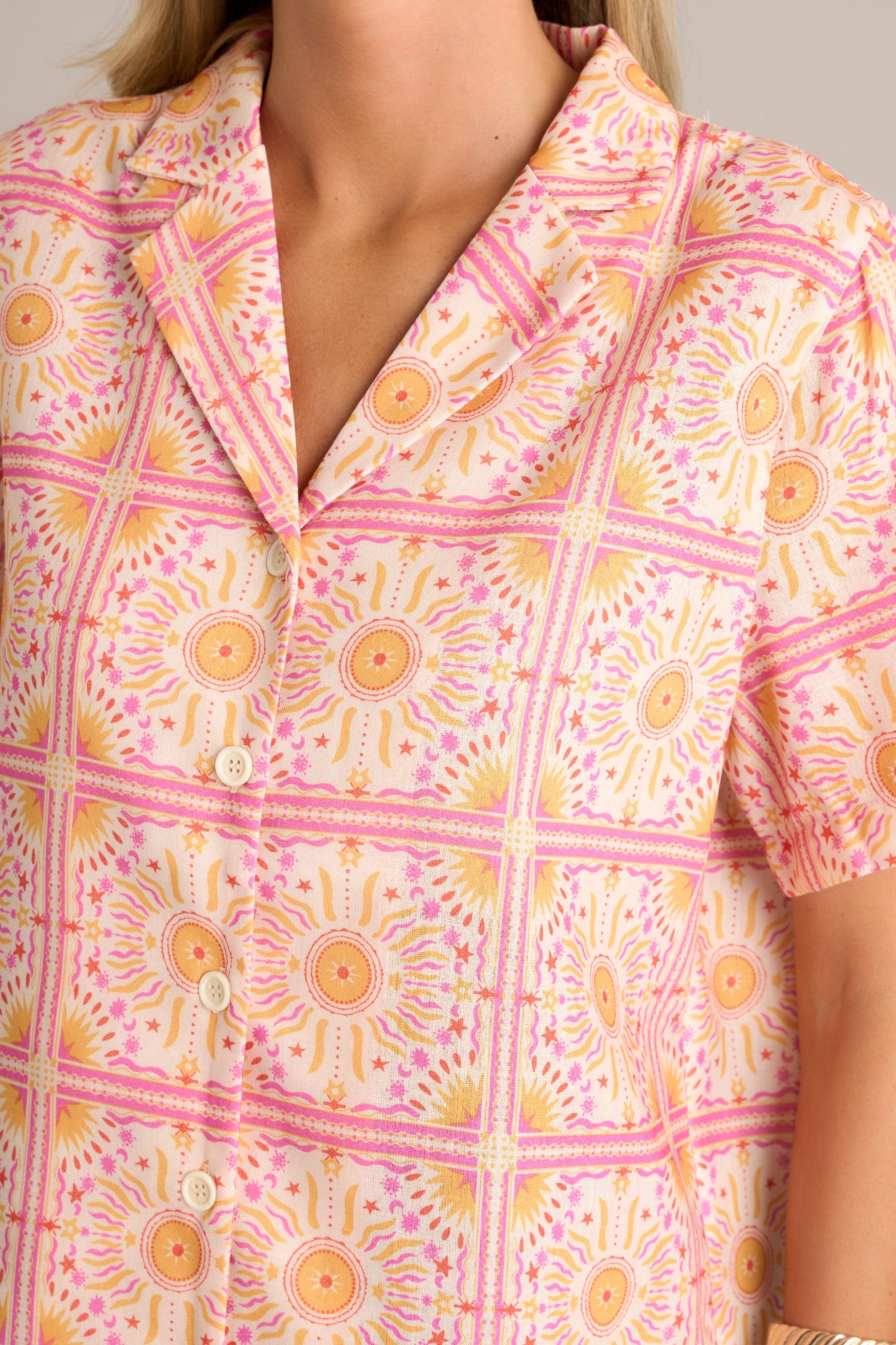 Close-up of the pink top showing the notched lapel collared neckline, full button front, and fun and unique print