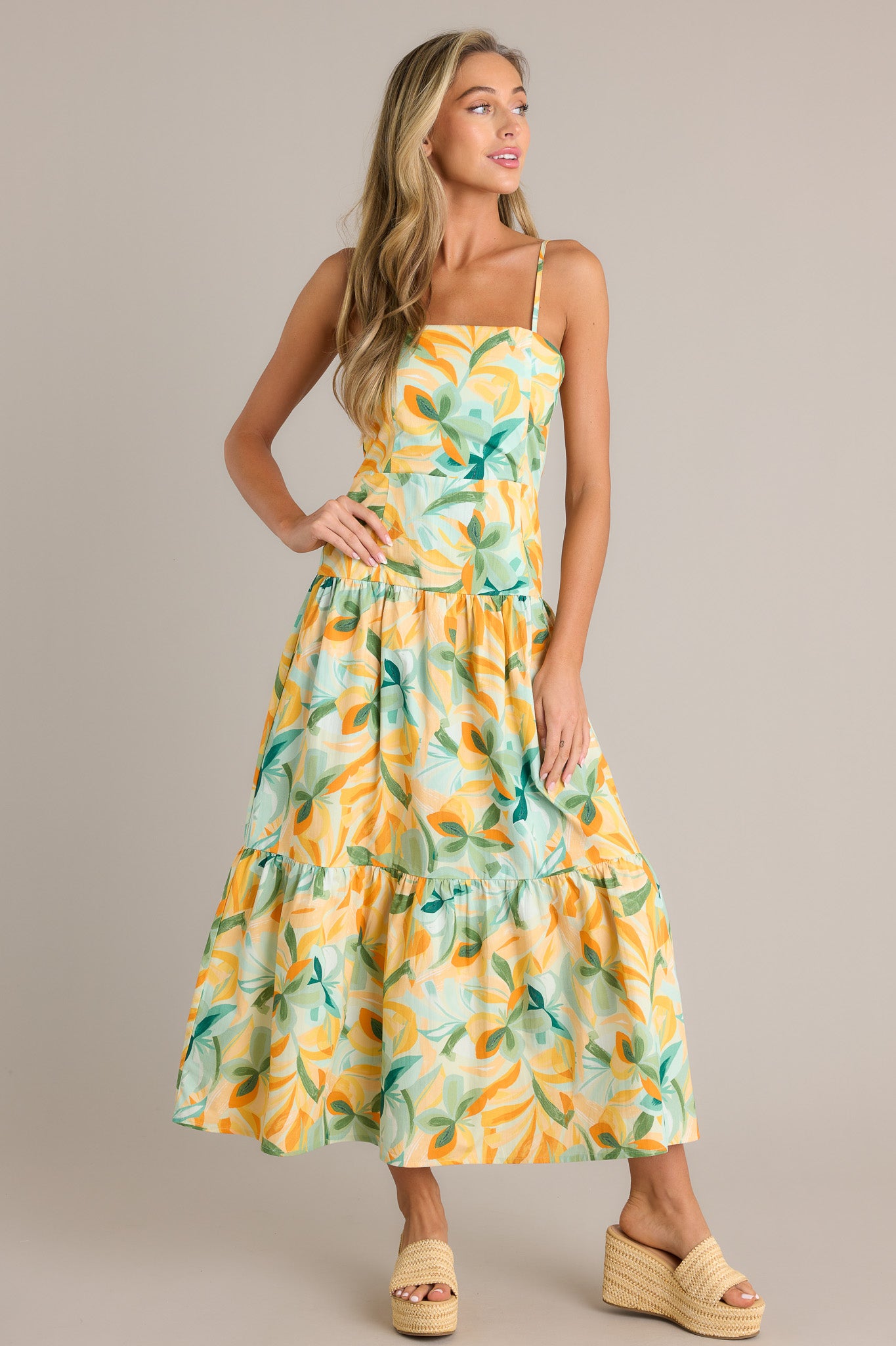 Action shot of a yellow midi dress displaying the fit and movement, highlighting the square neckline, discreet side zipper, smocked back insert, tiered design, and flowing silhouette.