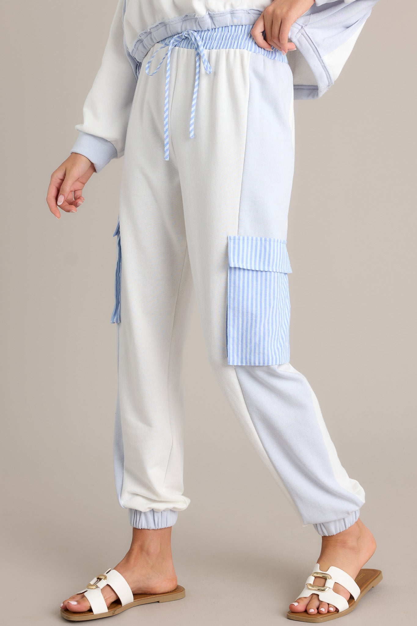 Side view of light blue joggers showcasing the high waisted design, elastic waistband, self-tie drawstring, functional cargo pockets, and elastic cuffed ankles.