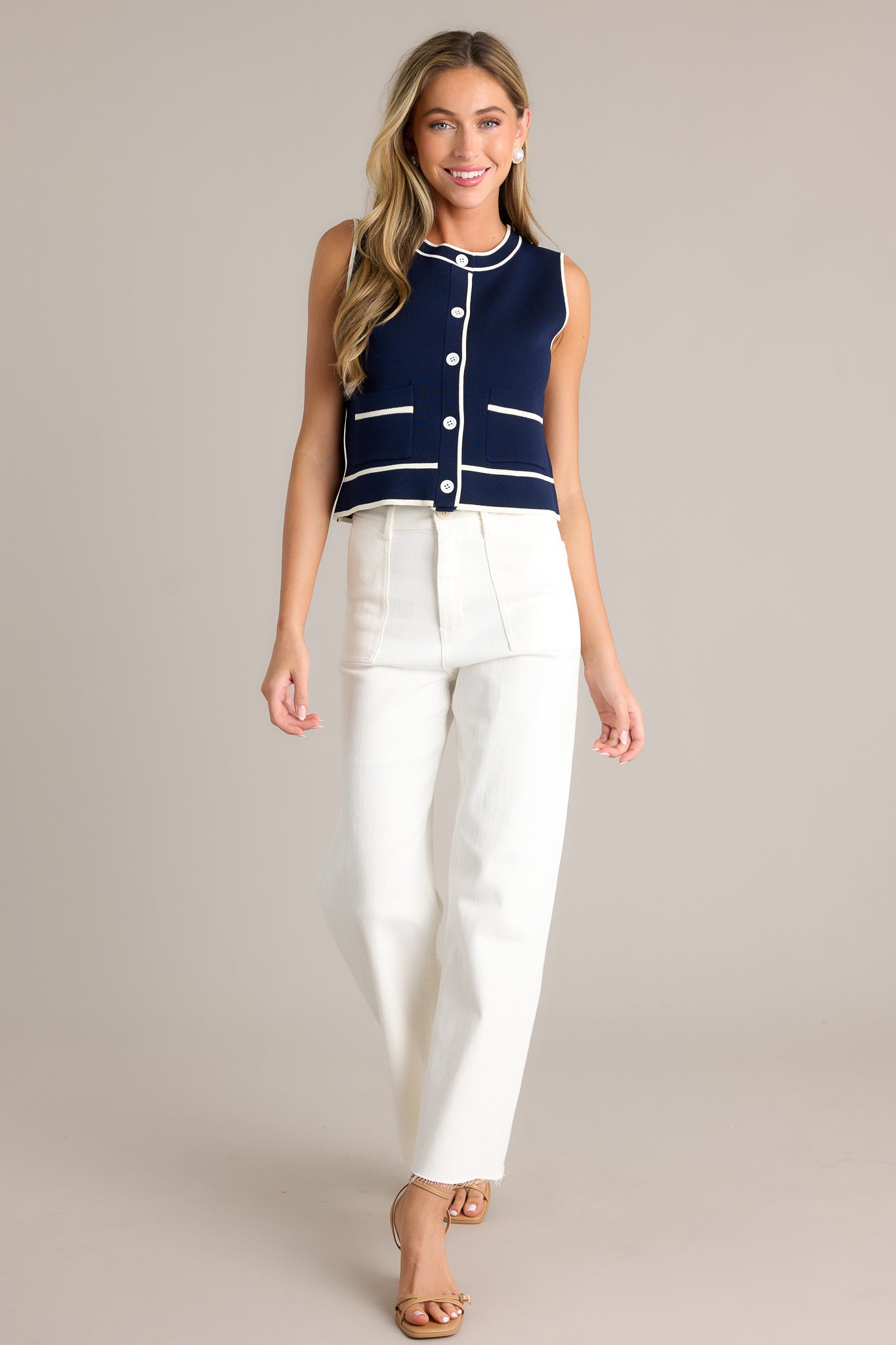 Action shot of white jeans with a high waisted design, a classic button & zipper closure, belt loops, functional front & back pockets, a wide leg design, and a raw hemline, highlighting the fit and flow of the jeans.