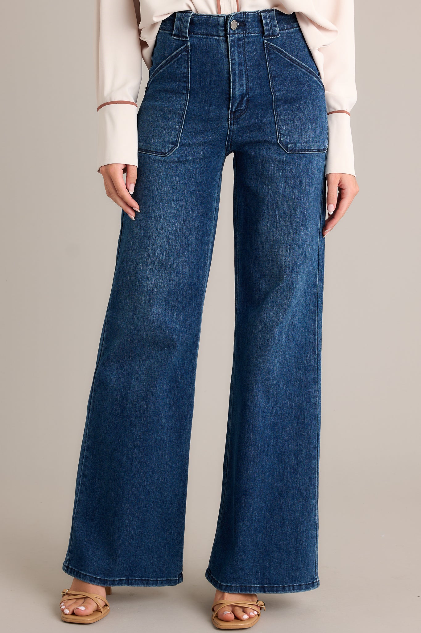 Front view of these dark wash jeans featuring a high waisted design, classic button zipper closure, belt loops, functional front patch pockets, and a flare leg.