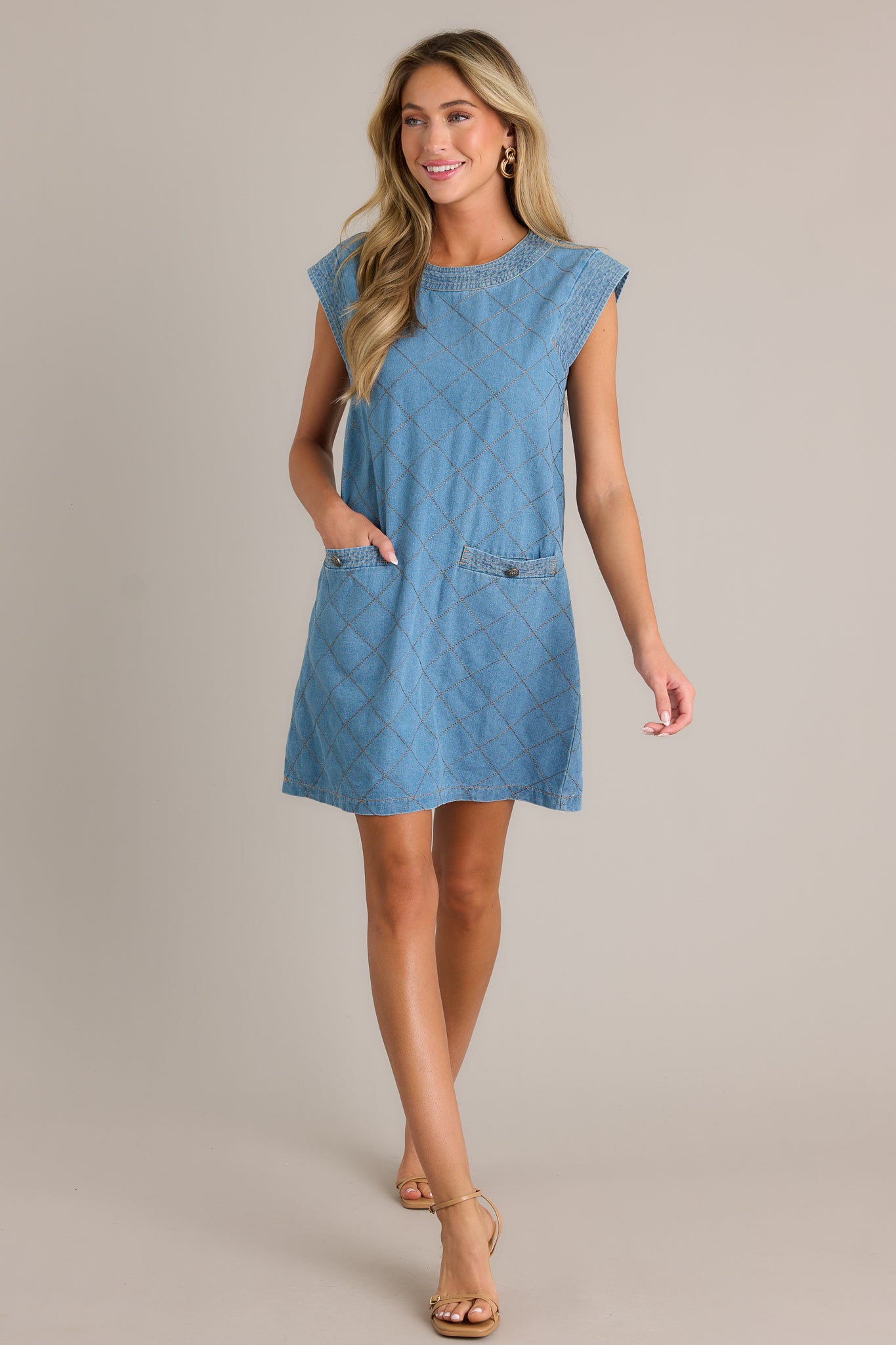 Action shot of a quilted mini dress displaying the fit and movement, highlighting the round neckline, cognac quilted design, and functional pockets.