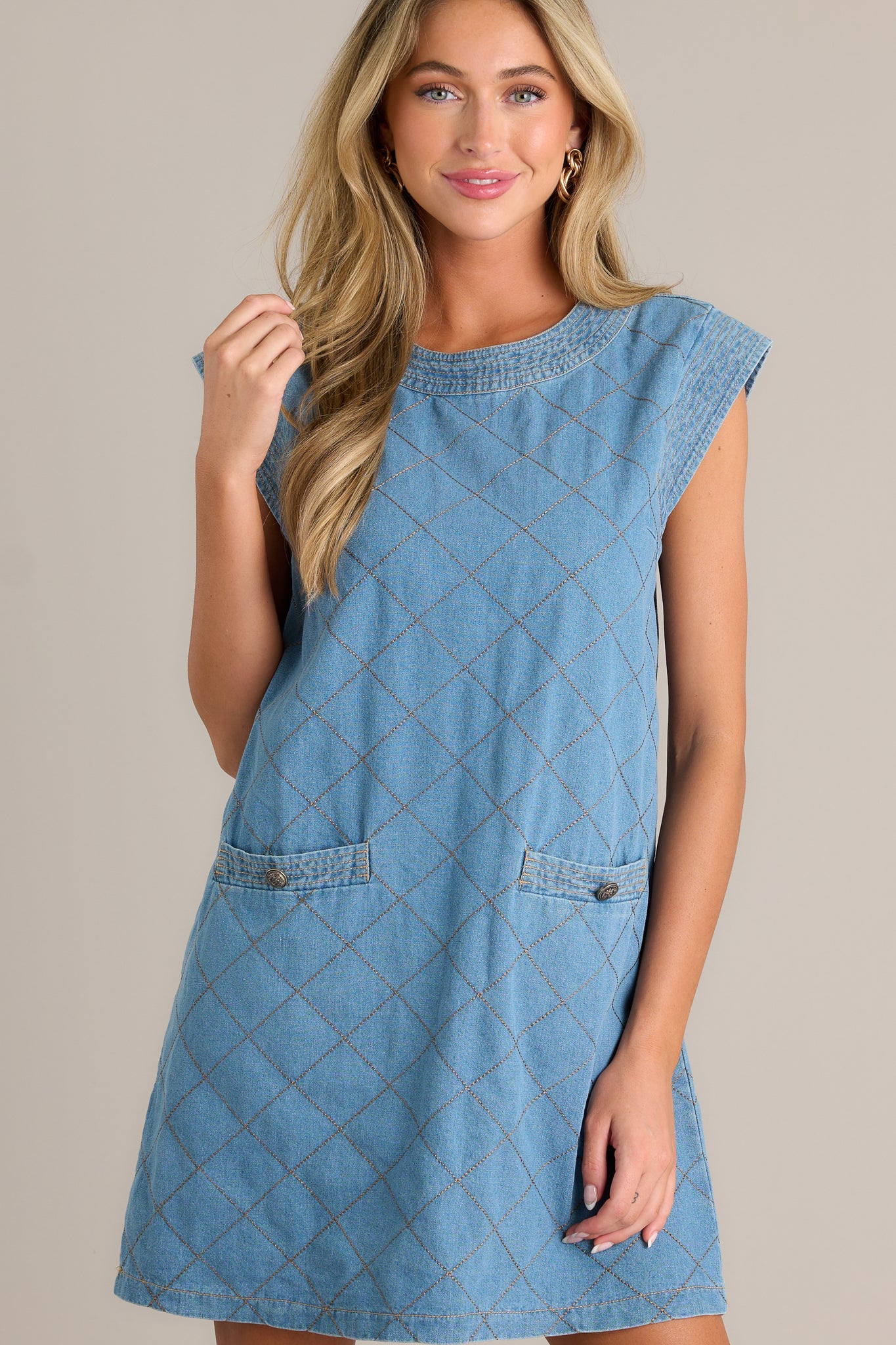 This quilted mini dress features a round neckline, cognac quilted design, a hidden back zipper, and functional pockets