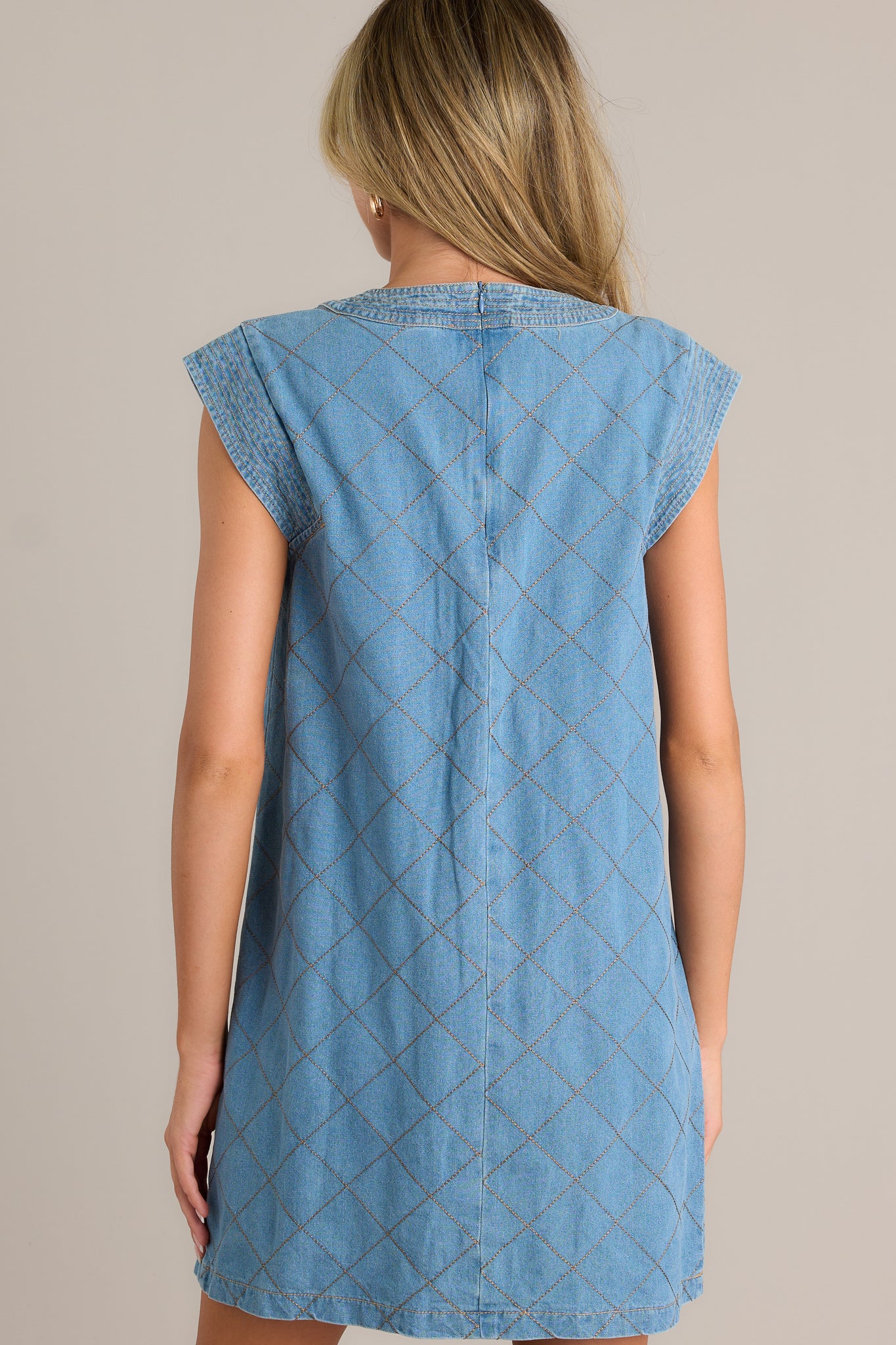 Back view of a quilted mini dress highlighting the hidden back zipper and overall fit.