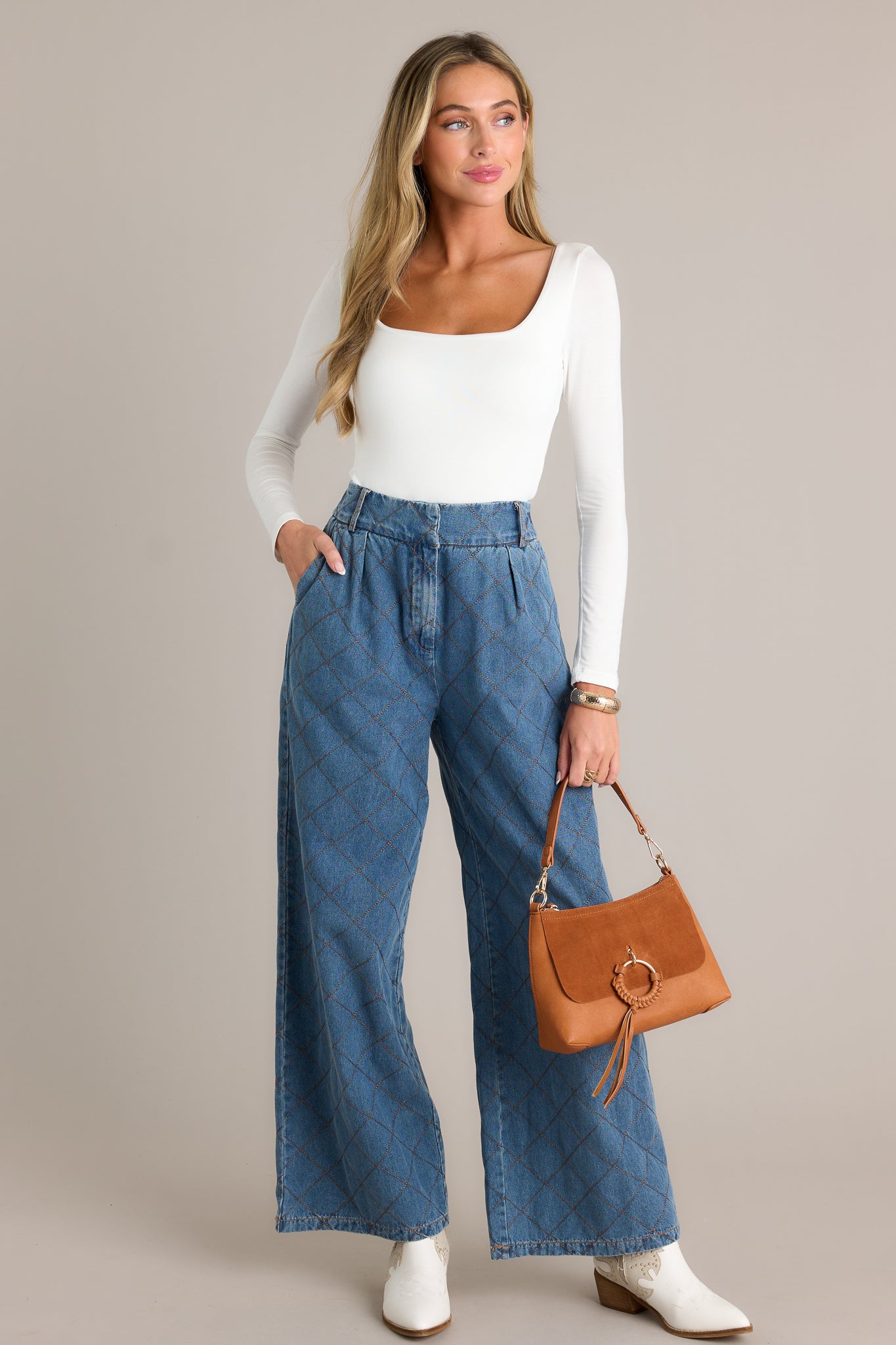 Full length view of quilted jeans with a high waisted design, a hook and bar closure, functional belt loops, hip pockets, a quilted design, and a wide leg