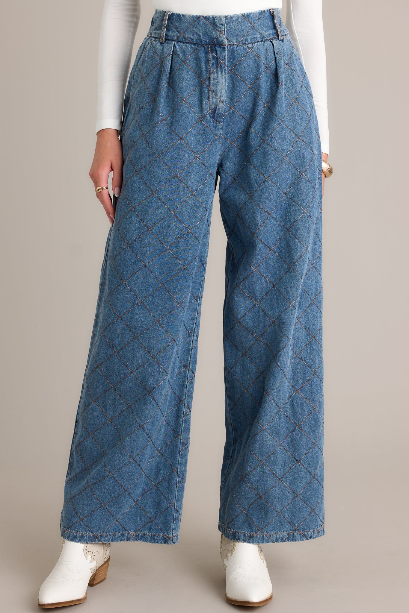 Front view of quilted jeans featuring a high waisted design, a hook and bar closure, functional belt loops, hip pockets, a quilted design, and a wide leg.