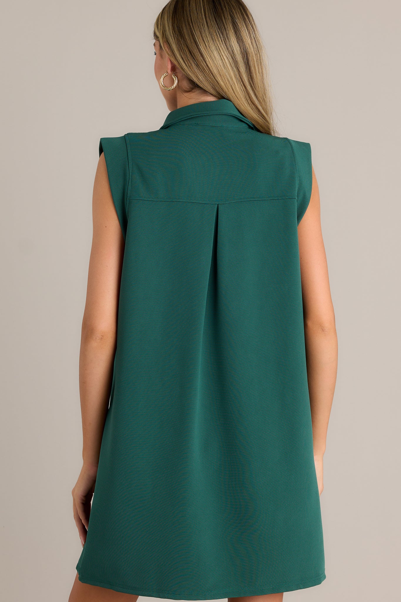 Back view of a green mini dress highlighting the overall fit, sleeveless design, and relaxed silhouette.