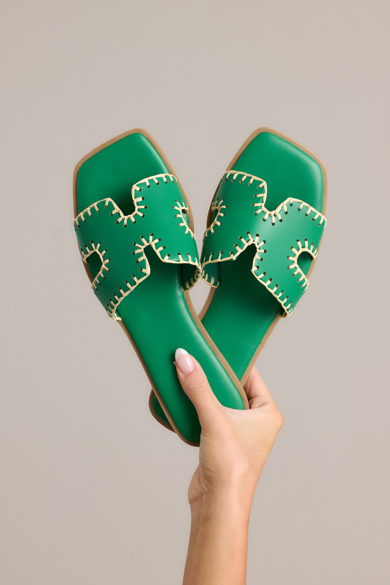 These green sandals feature a square toe, a slip on design, a strap with cutouts over the top of the foot beige stitch detailing, and a high contrasting sole.