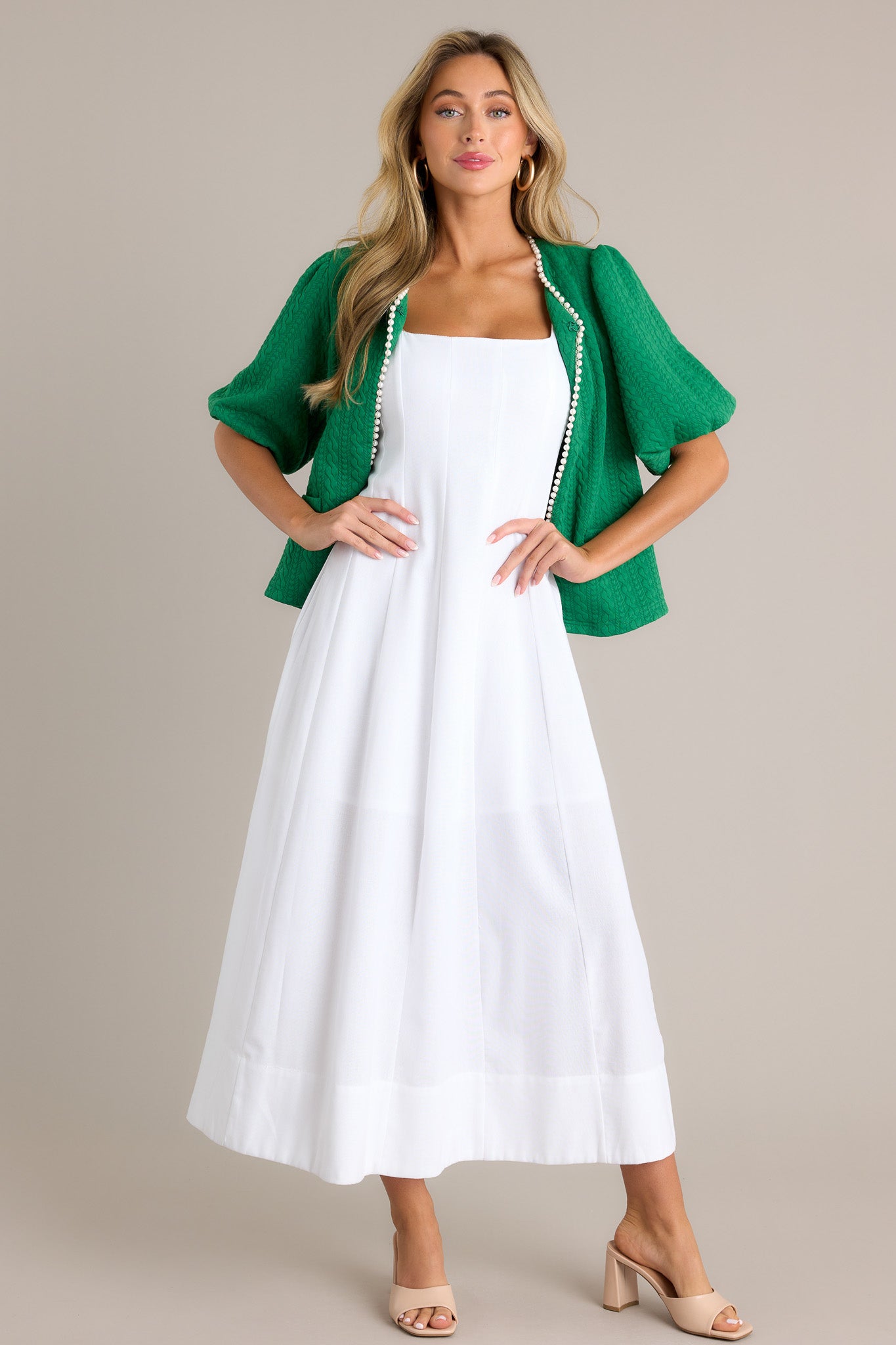 This white maxi dress features a square neckline, thick straps, a discrete back zipper, a flowing silhouette, and a thick hemline.