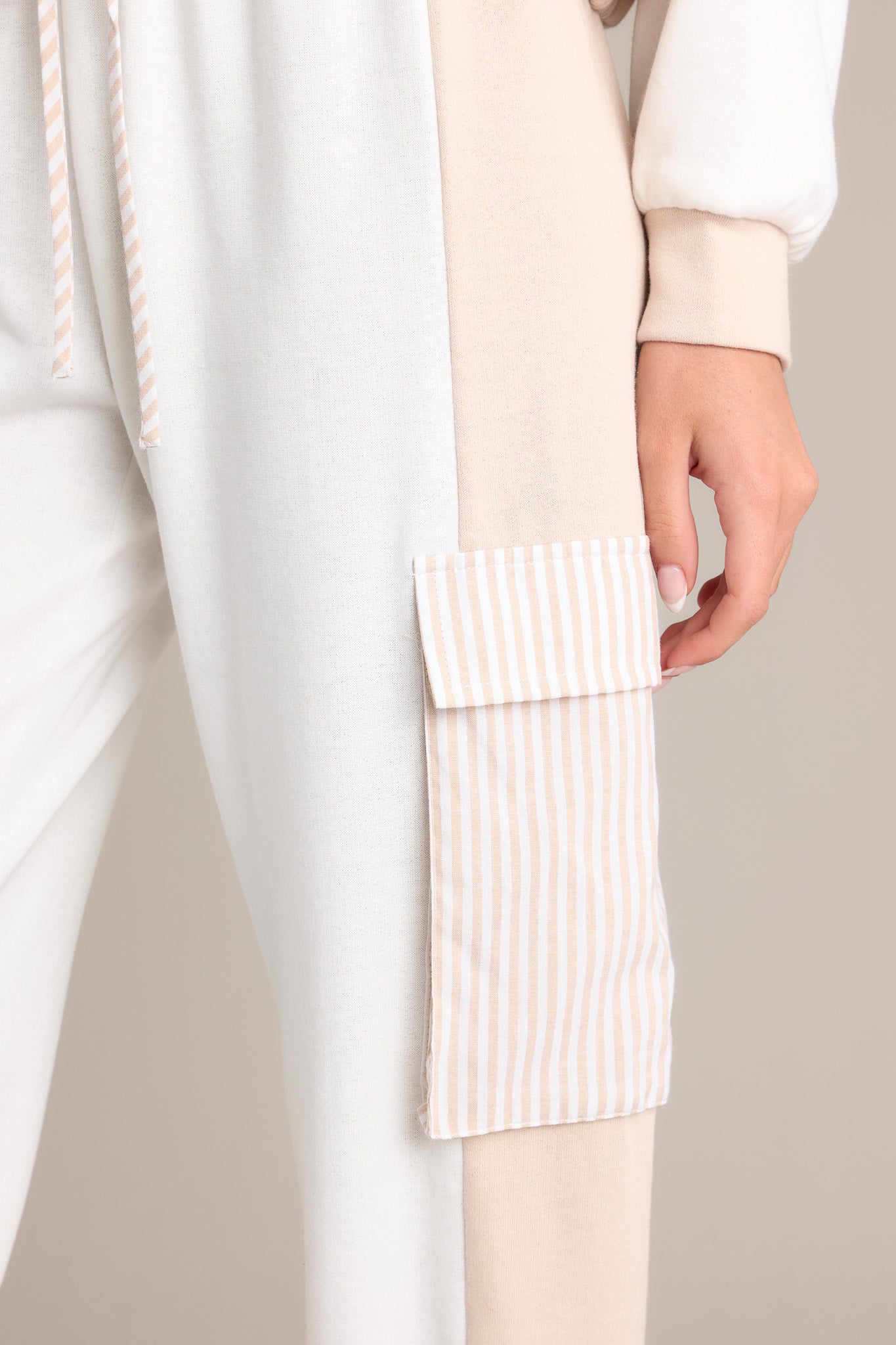 Close-up of the beige joggers showing the high waisted design, self-tie drawstring, and functional cargo pockets.