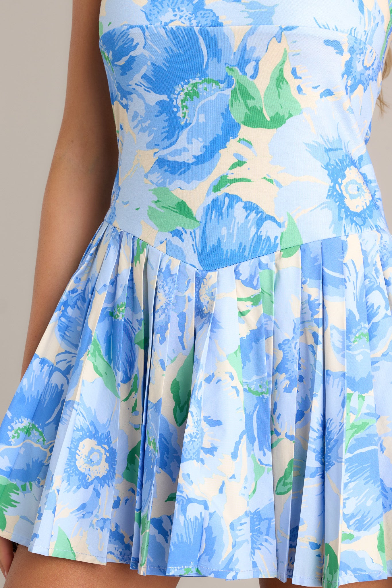 Close-up of the blue mini dress showing the square neckline, thin straps, discrete side zipper, and floral pattern.