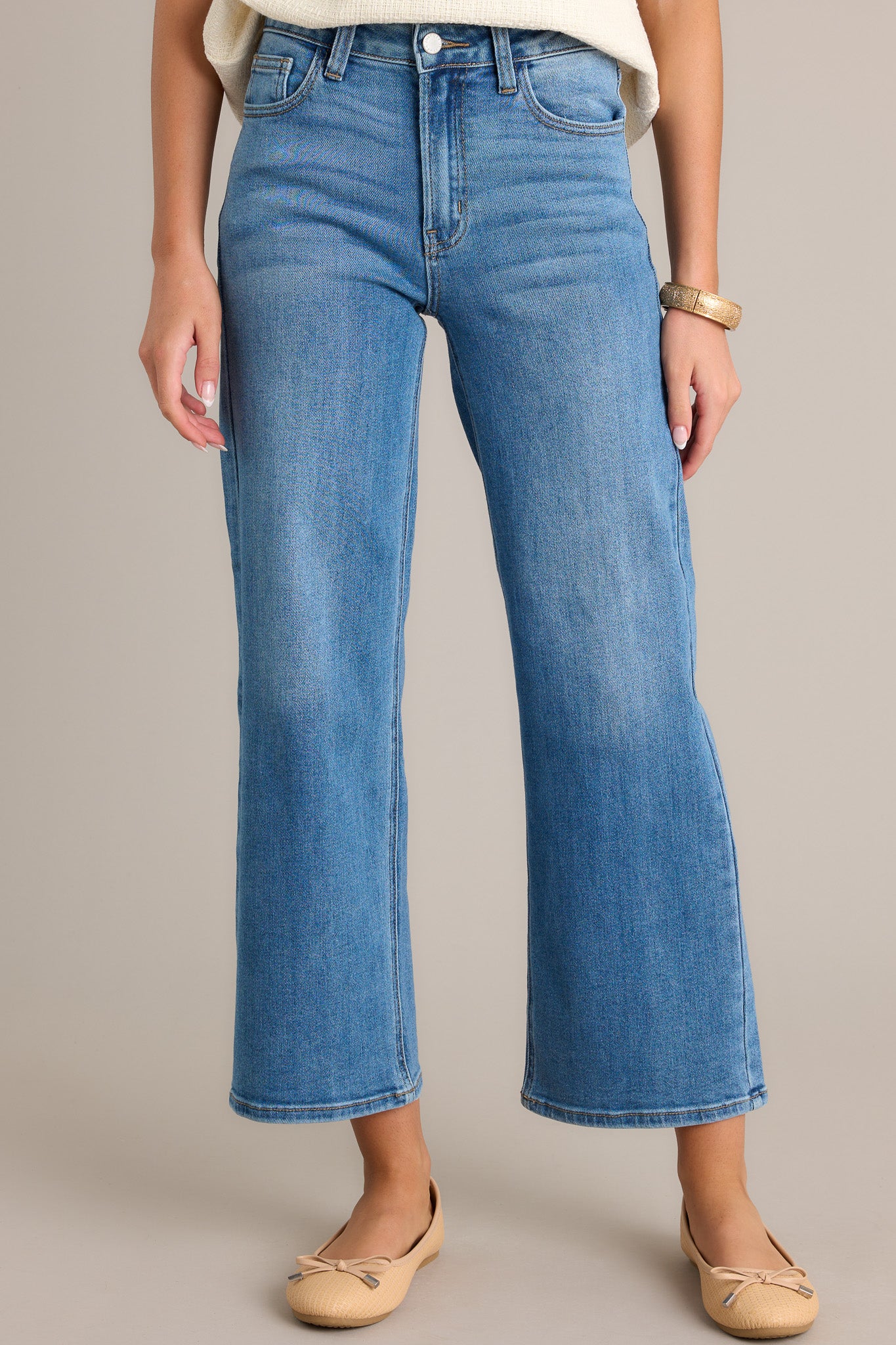 Front view of jeans featuring a high waisted design, classic button and zipper closure, belt loops, functional front and back pockets, and a cropped length.