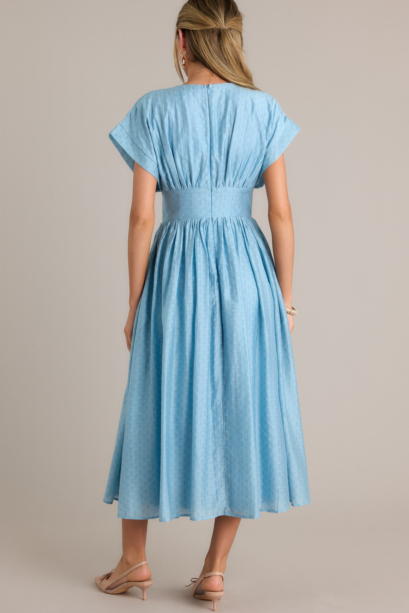 Back view of a sky blue midi dress highlighting the discrete back zipper, thick waistband, and overall fit.