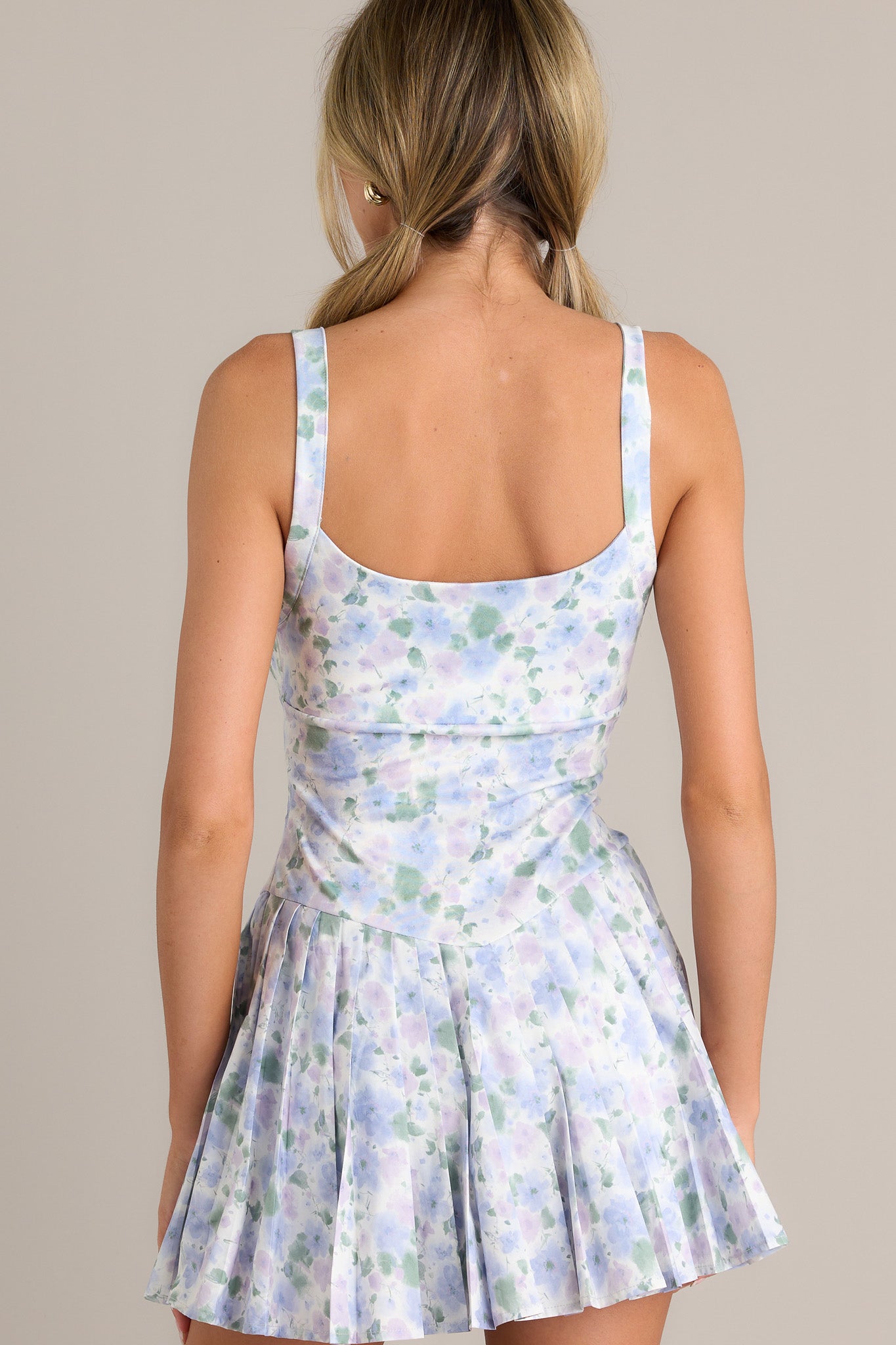 Back view of a periwinkle mini dress highlighting the thin straps, pastel floral pattern, and overall fit.