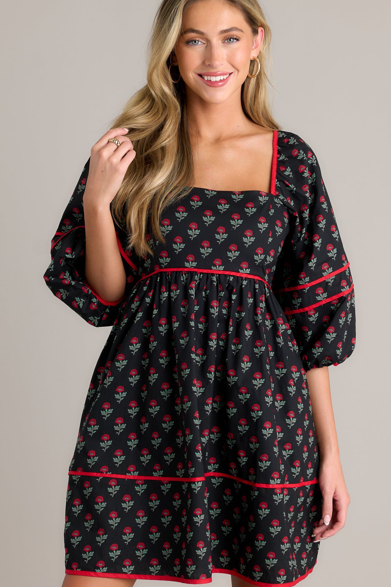 Front view of a floral puff sleeve dress featuring a square neckline, functional hip pockets, a tiered design, a self-tie back, a smocked back, and elastic cuffed half sleeves.