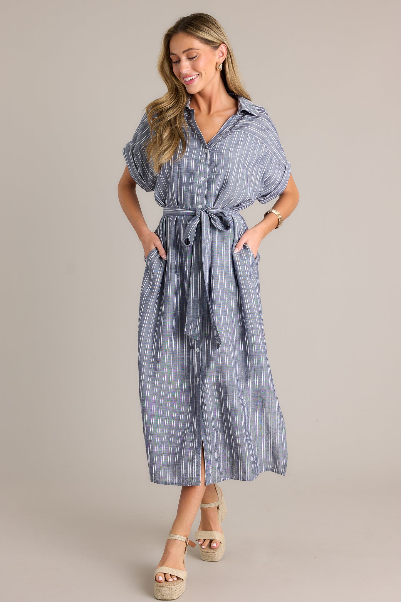 Action shot of a blue dress displaying the fit and movement, highlighting the functional button front, optional self-tie belt, collared neckline, and cuffed short sleeves.