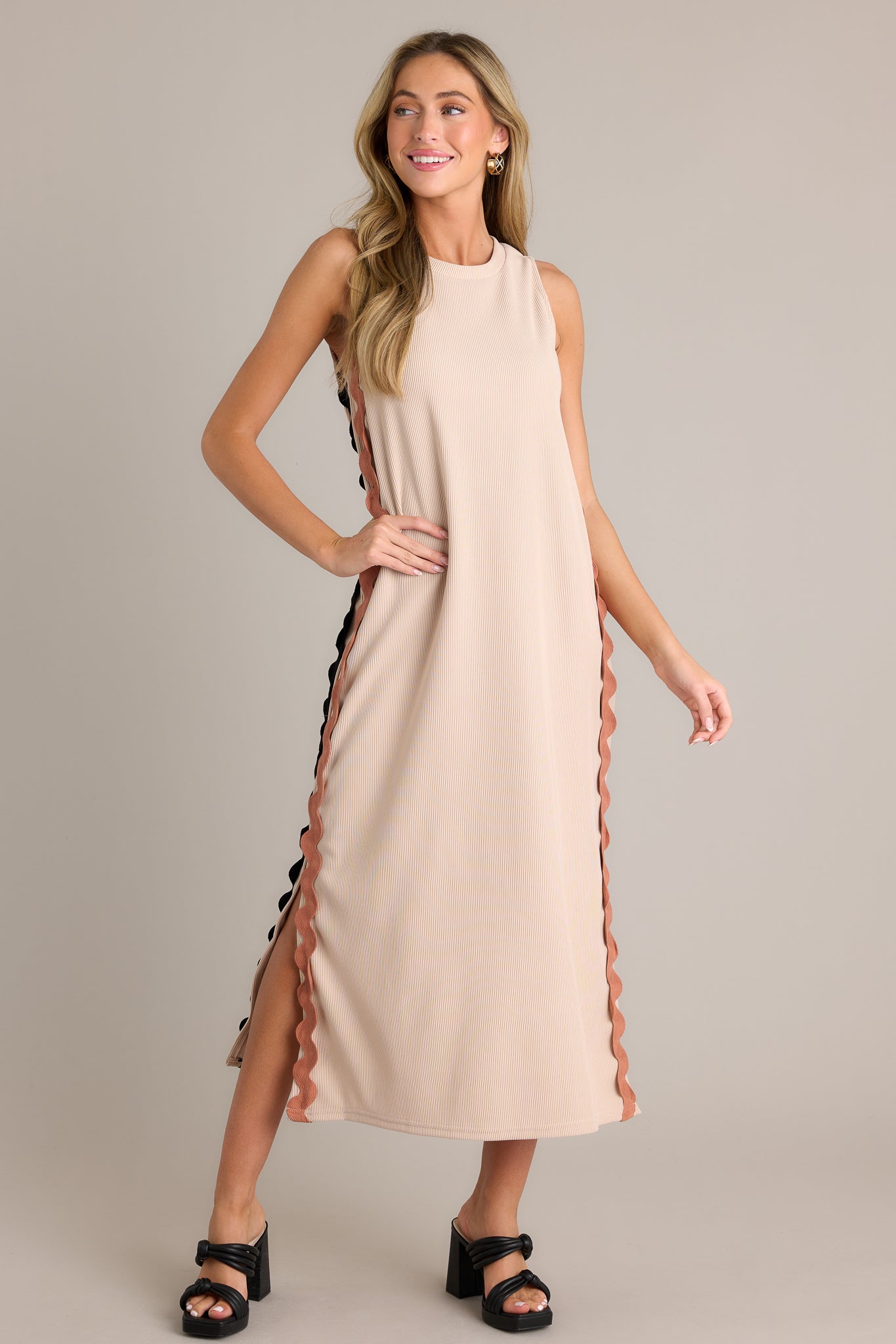 This taupe midi dress features a crew neckline, a ribbed material, two-toned ricrac side detailing, side slits, and a sleeveless design.