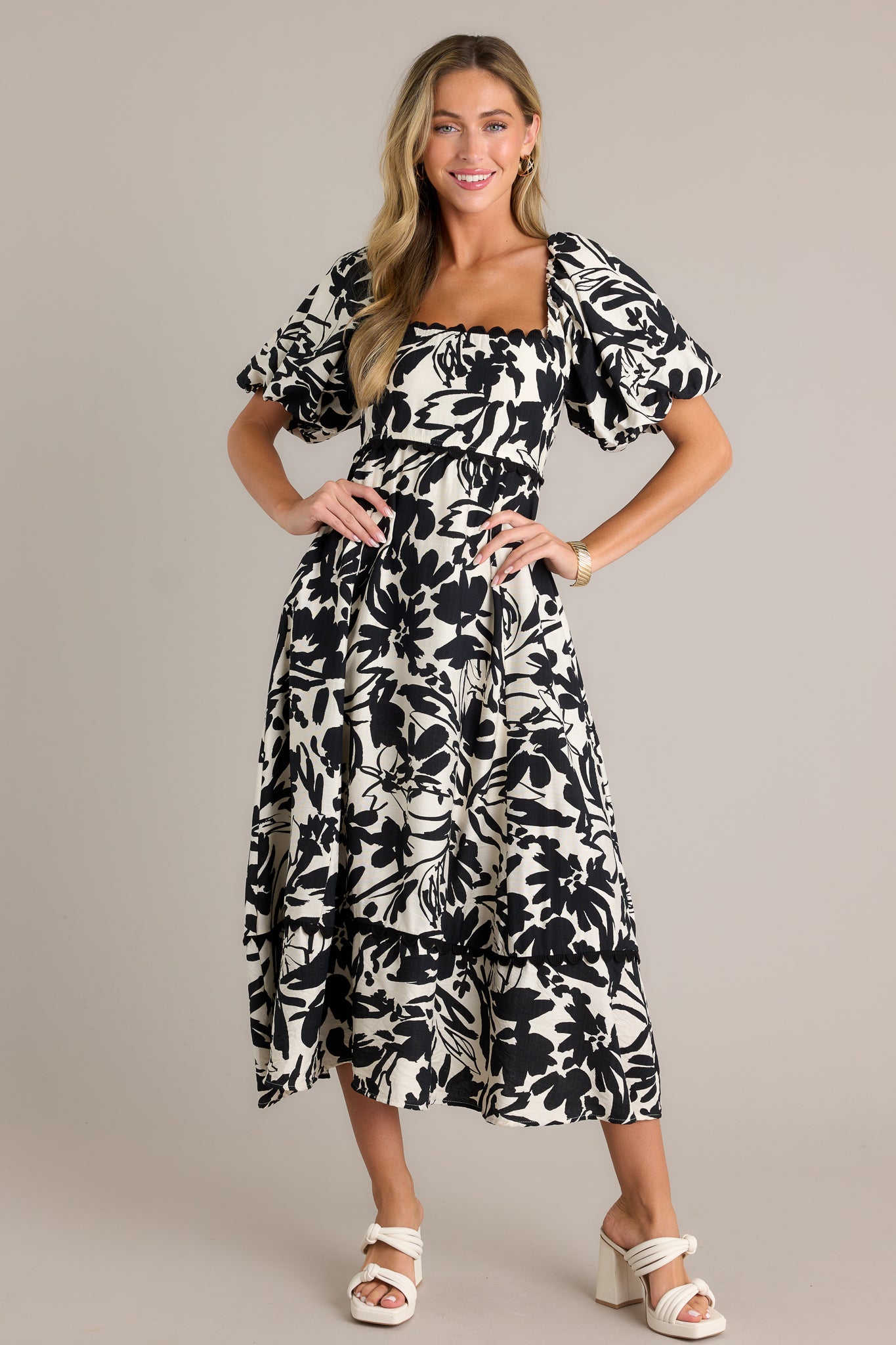 Front view of an ivory maxi dress showcasing a ruffled square neckline, functional hip pockets, a smocked back insert, elastic cuffed puff sleeves, a tiered design, and a flowing silhouette.