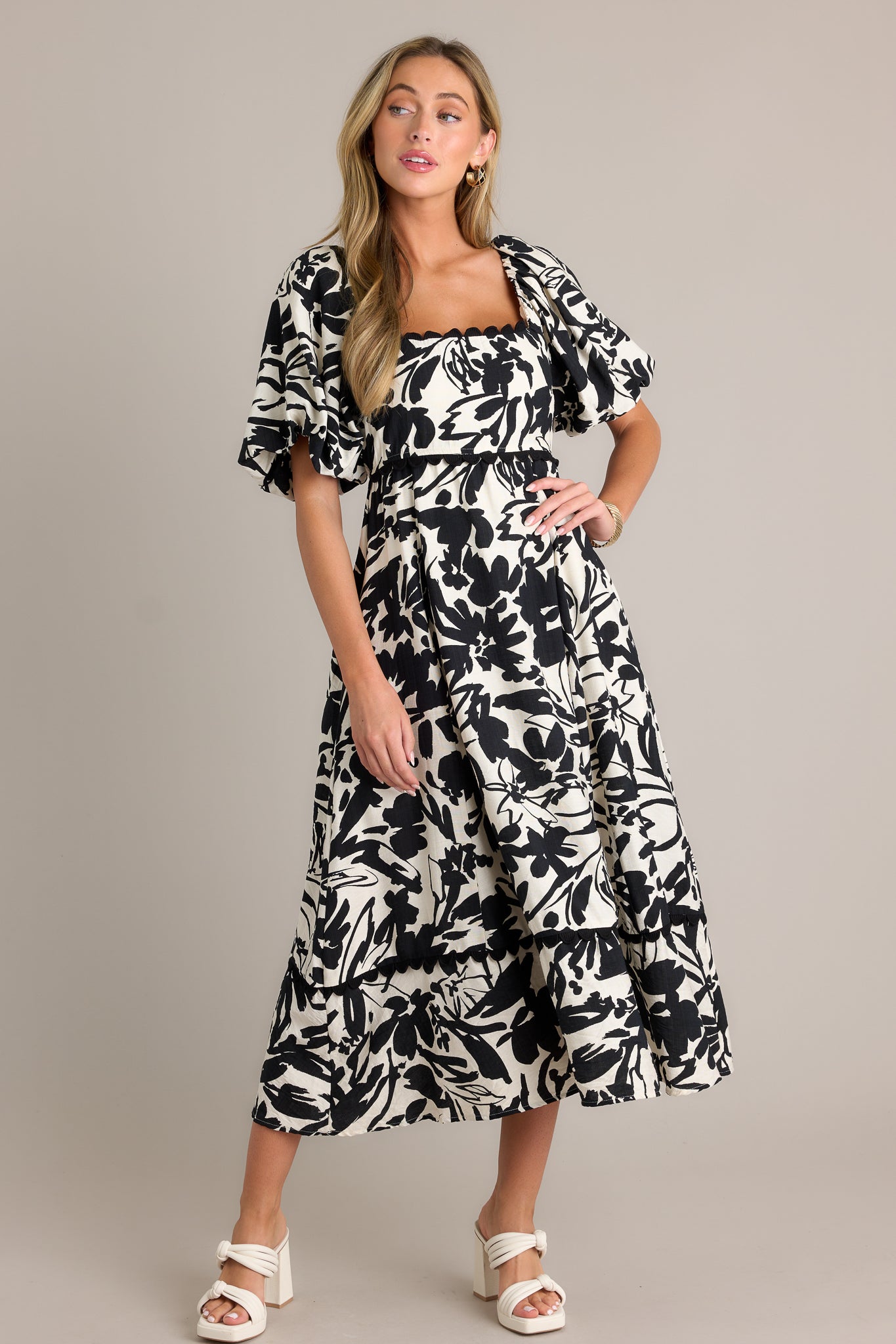 Full length view of an ivory maxi dress with a ruffled square neckline, functional hip pockets, a smocked back insert, elastic cuffed puff sleeves, a tiered design, and a flowing silhouette