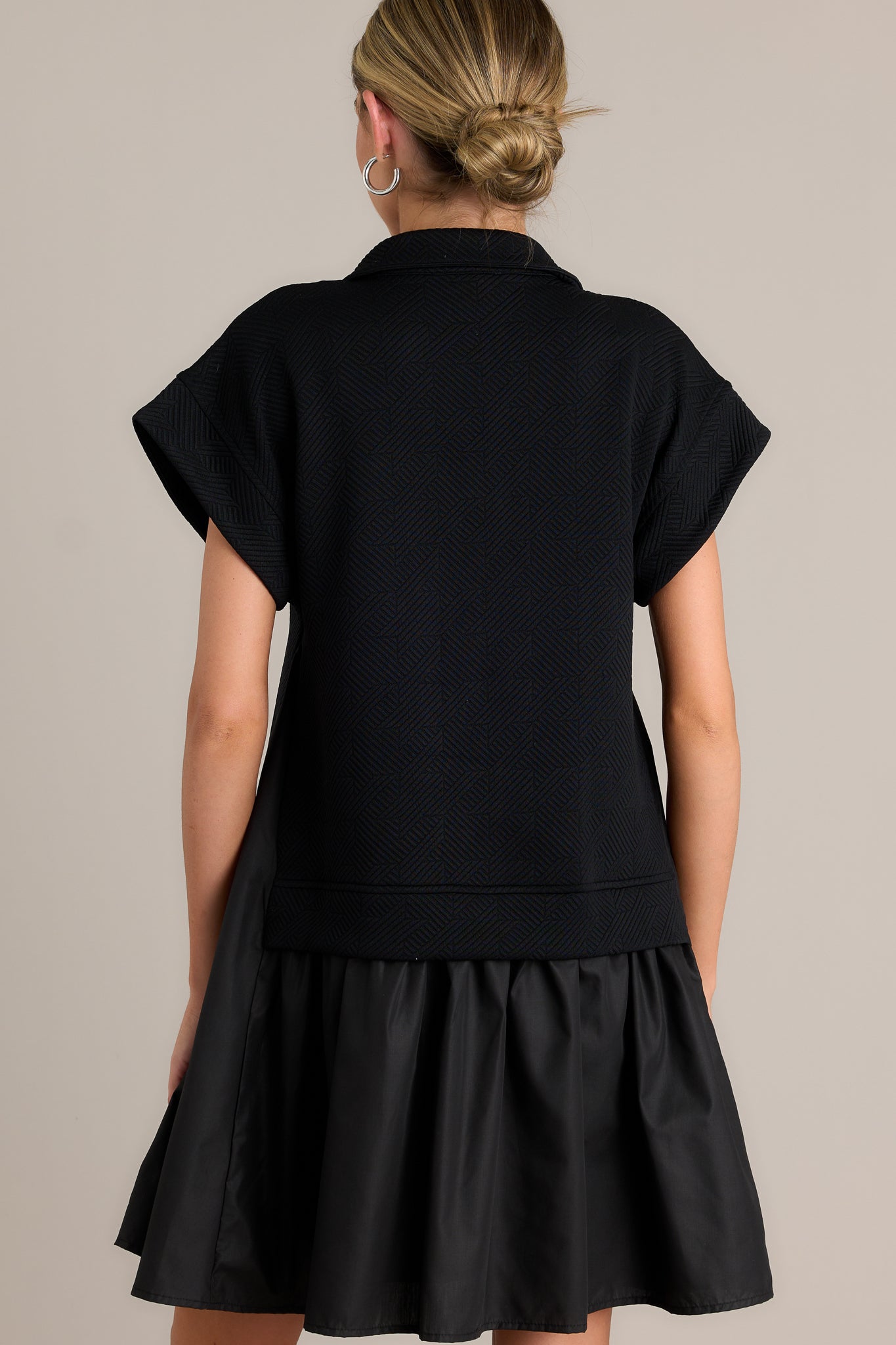 Back view of a black quilted dress highlighting the overall fit, quilted bodice, and tiered design.