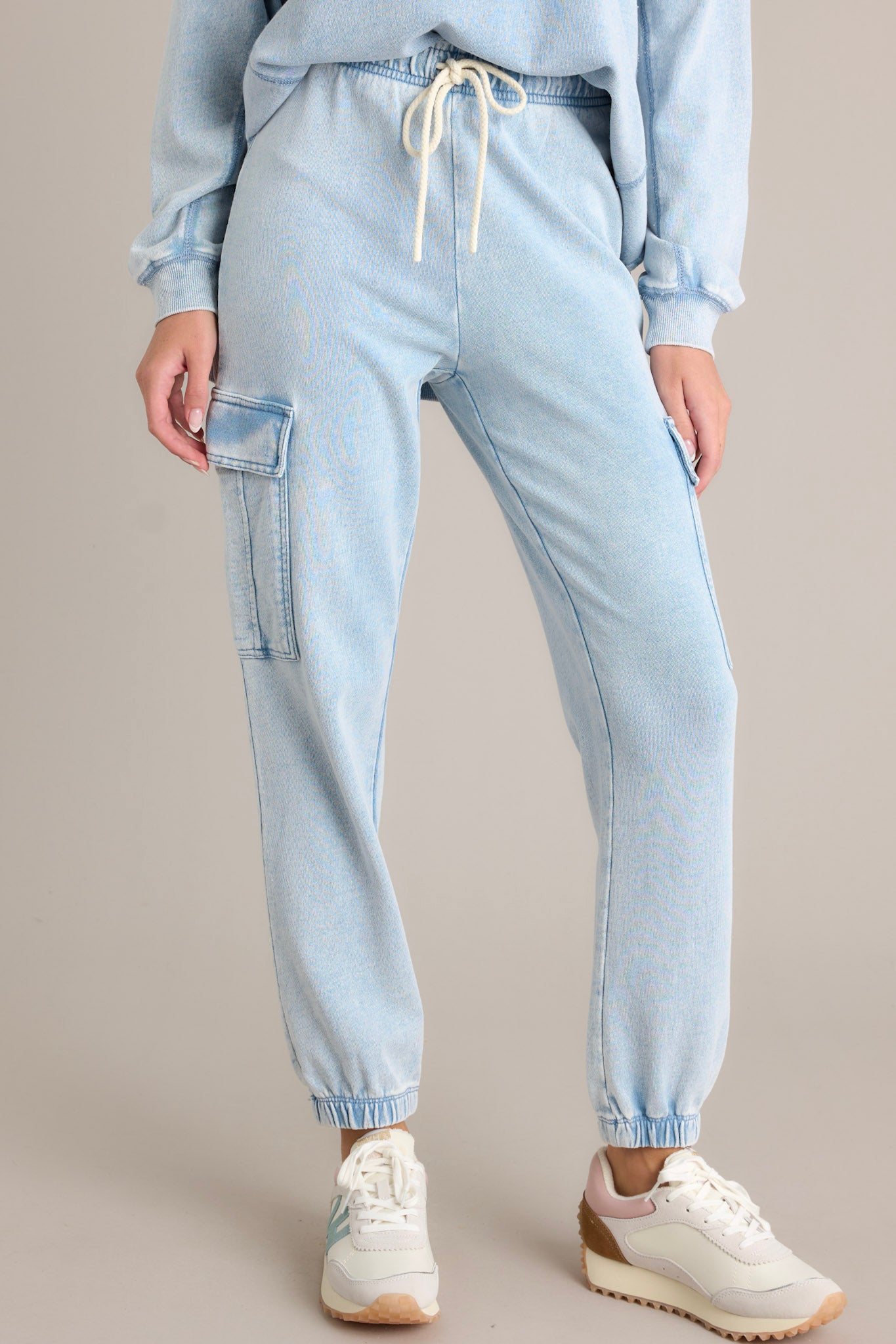 These blue joggers feature an elastic waistband with a self-tie drawstring, large side pockets, a washed design, and elastic cuffed ankles.