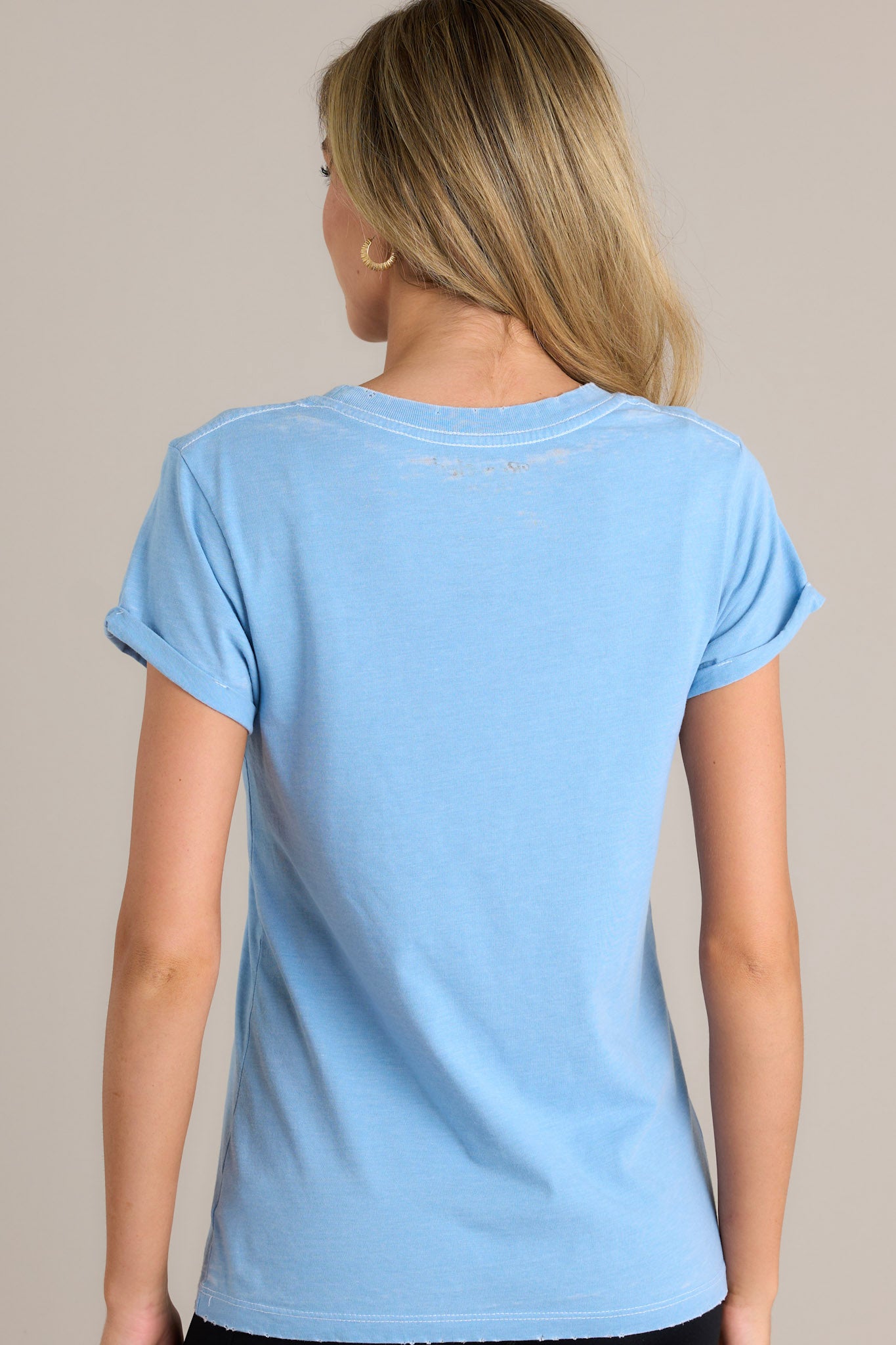 Back view of this washed denim tee that  features a ribbed crew neckline, a soft vintage washed fabric, rolled short sleeves, and distressed hems