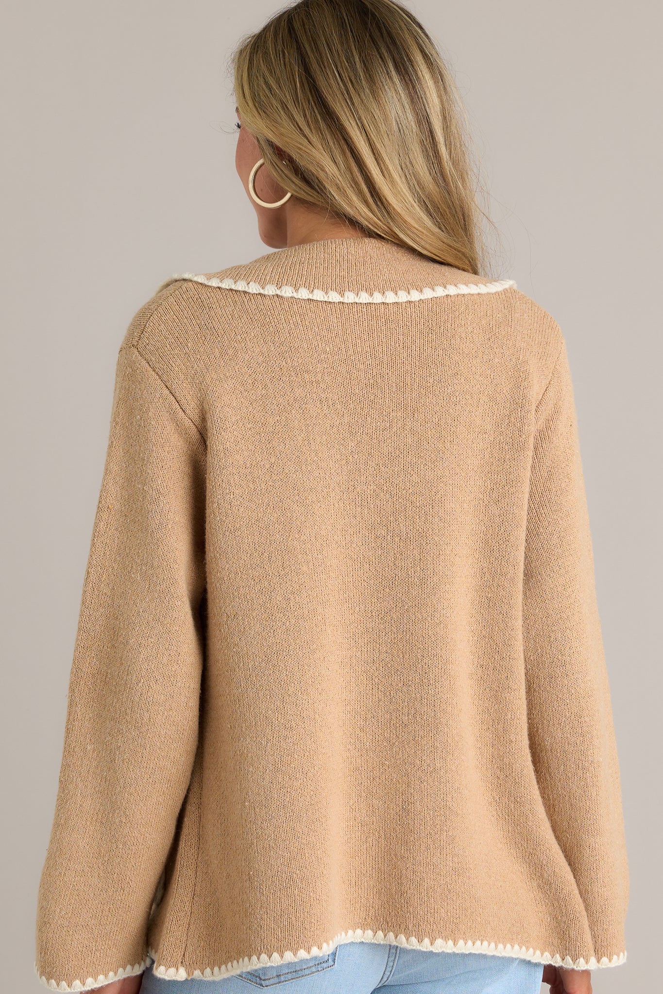 Back view of a tan jacket highlighting the overall fit, functional pockets, and ivory knitted trim.